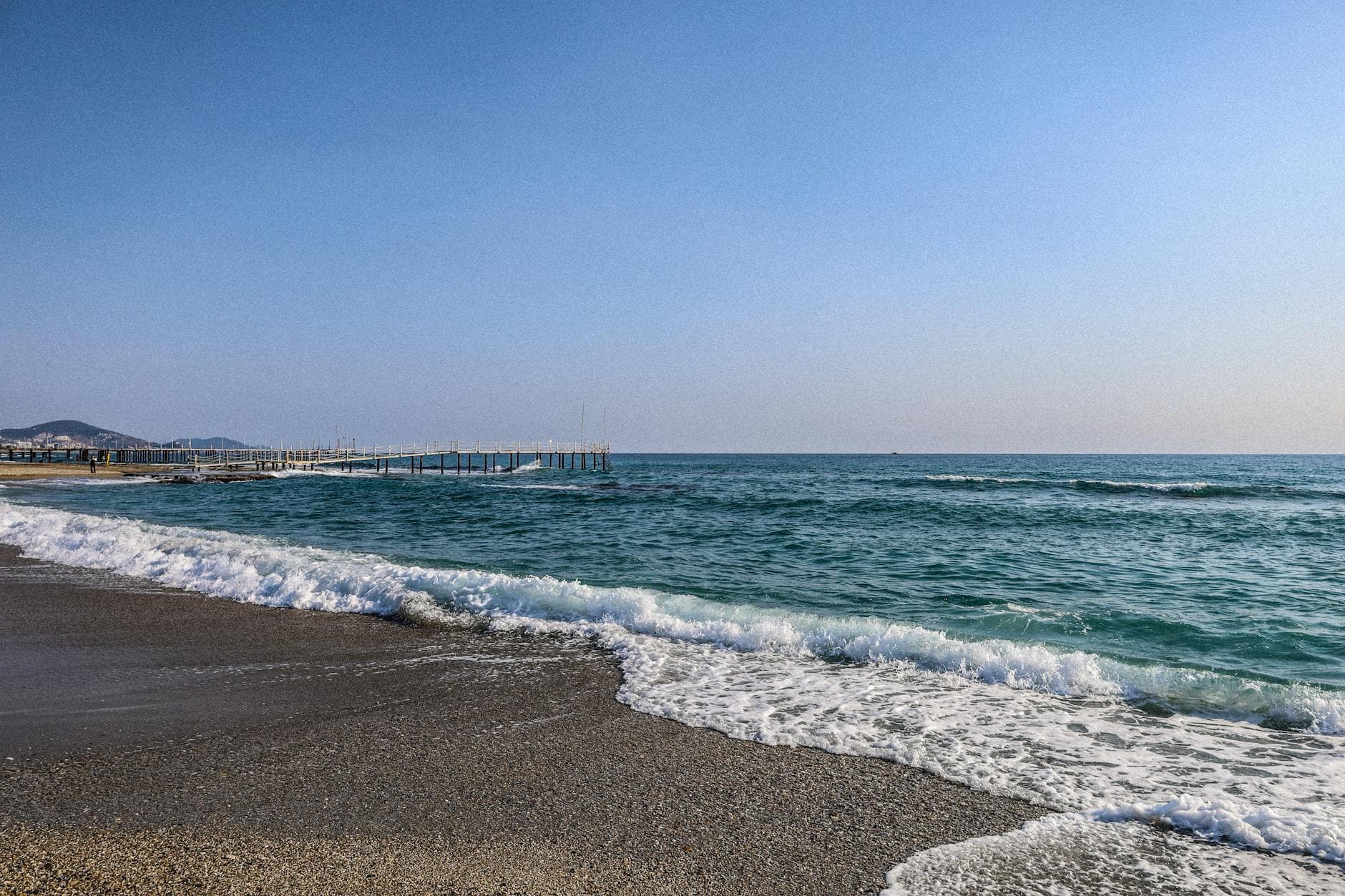 Peaceful beach scenery in Alanya, Turkey with gentle waves and clear skies.