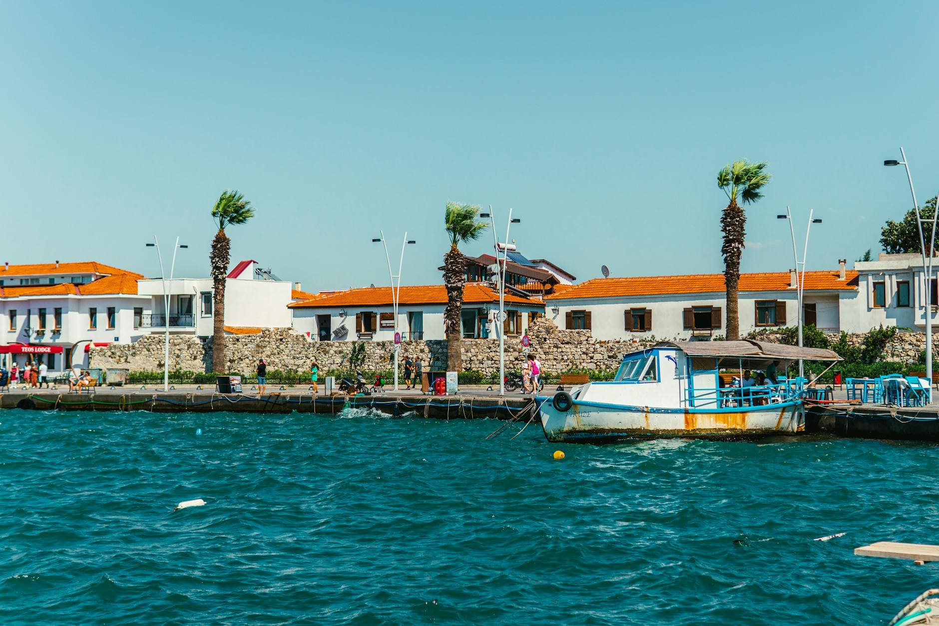 Picturesque waterfront scene in Sığacık, İzmir, Turkey with a boat docked on a sunny day.