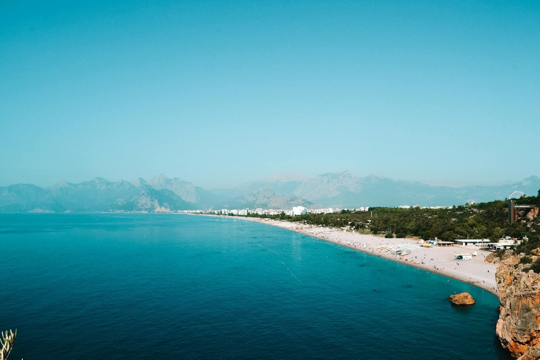 A breathtaking aerial view of Konyaalti Beach with turquoise waters and distant mountains in Turkey.