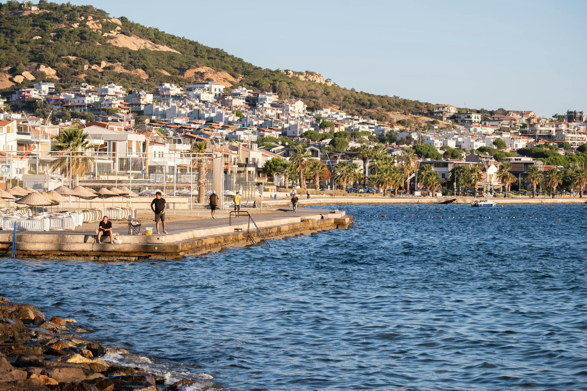 Scenic view of the coastline in Foça, İzmir, Turkey during sunset with people enjoying the seaside.
