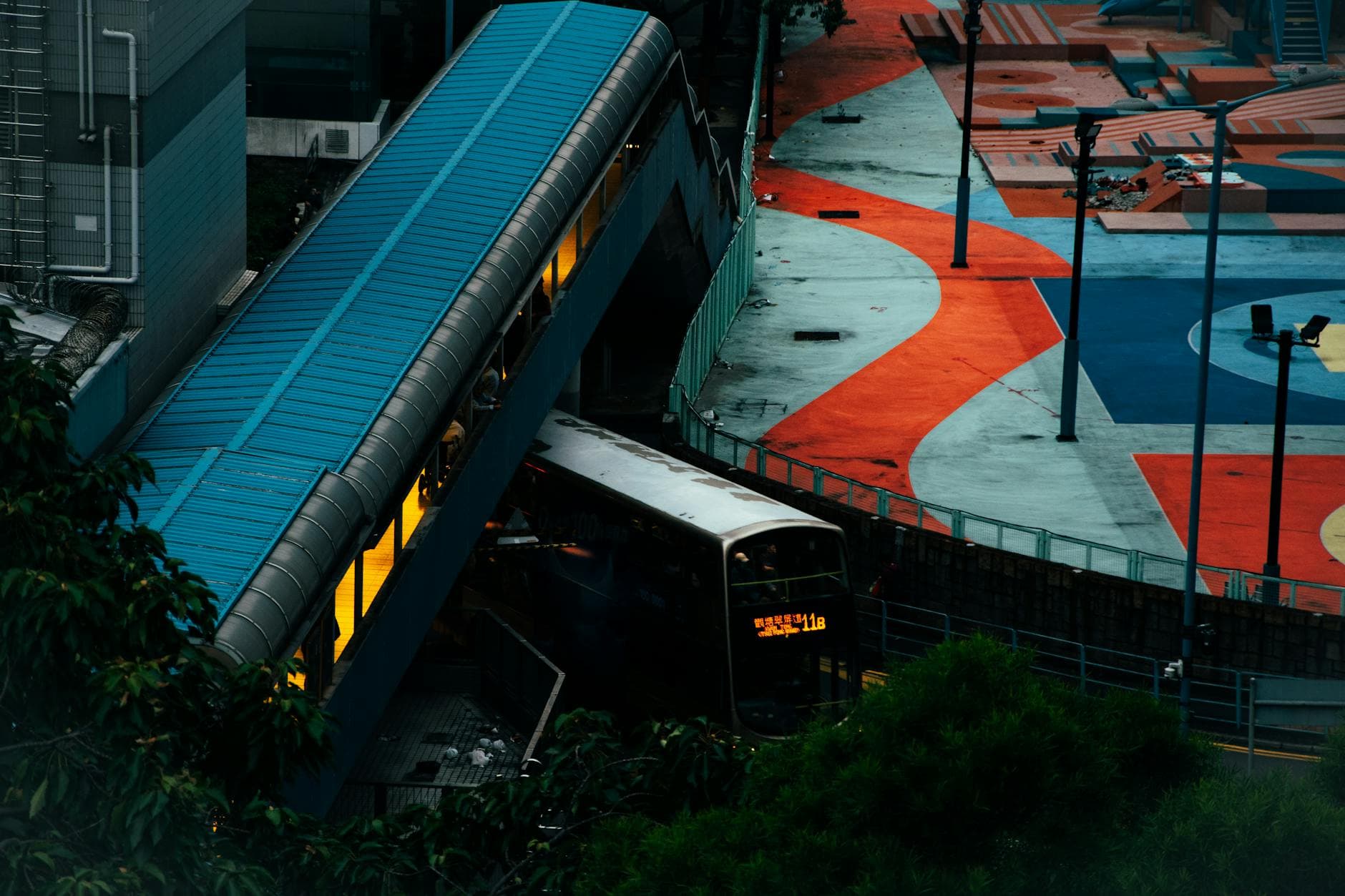 Aerial view of a modern bus station with vibrant geometric designs and a bus arriving.