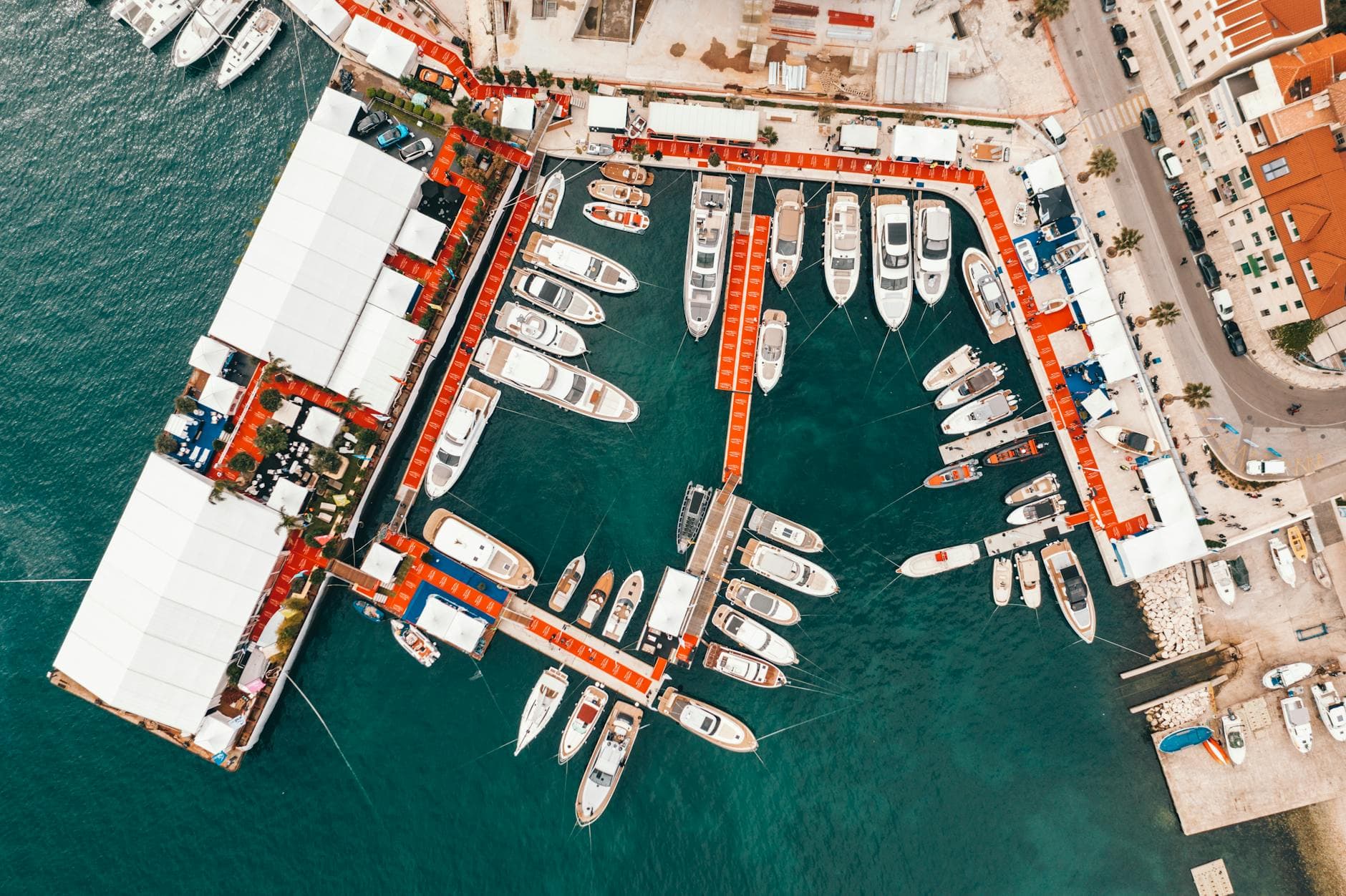 Picturesque aerial view of modern yachts moored in port located in Dubrovnik Old Town with red roofed historical buildings