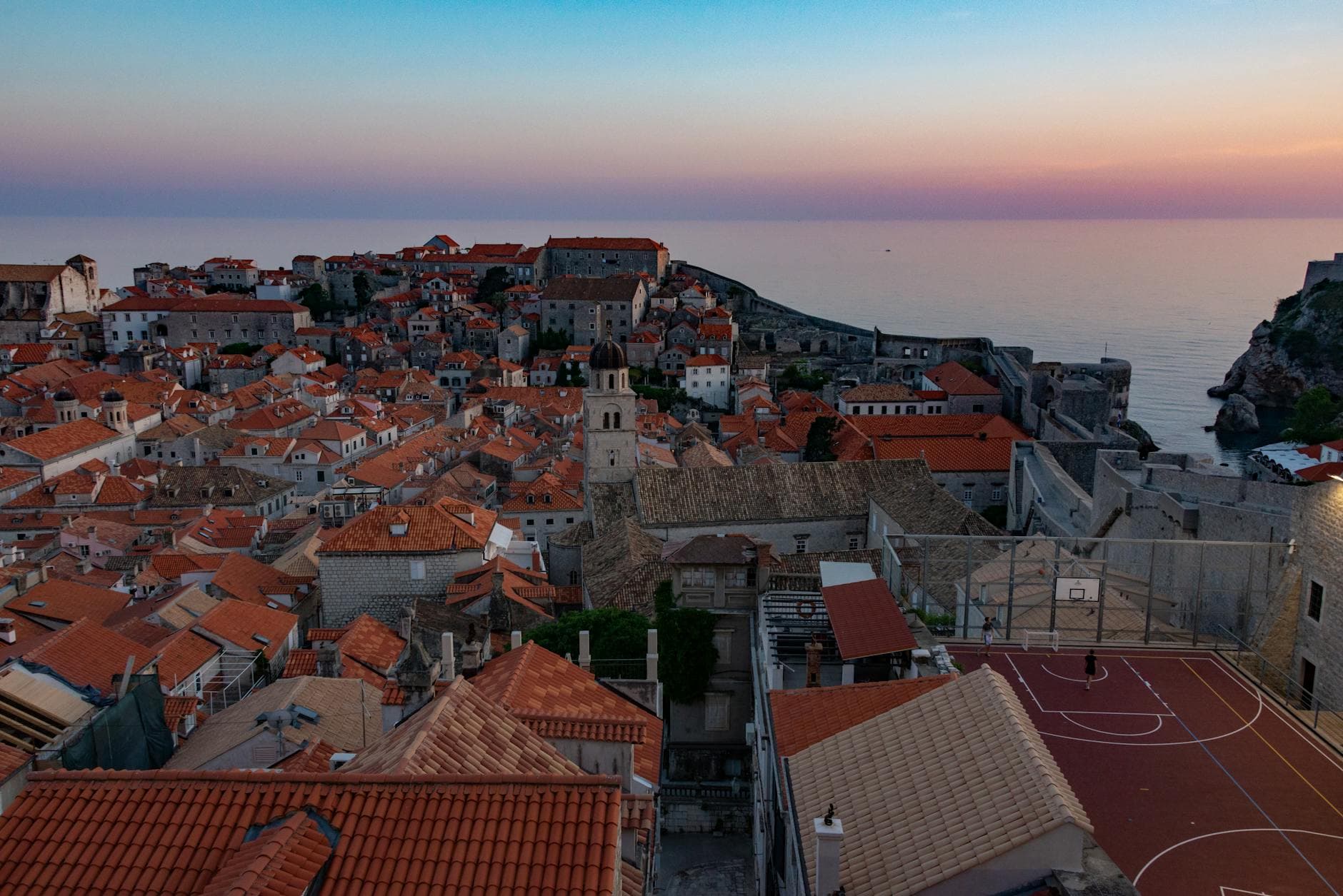 Stunning aerial view of Dubrovnik's rooftops and coastline at sunset, capturing the city's historic charm.