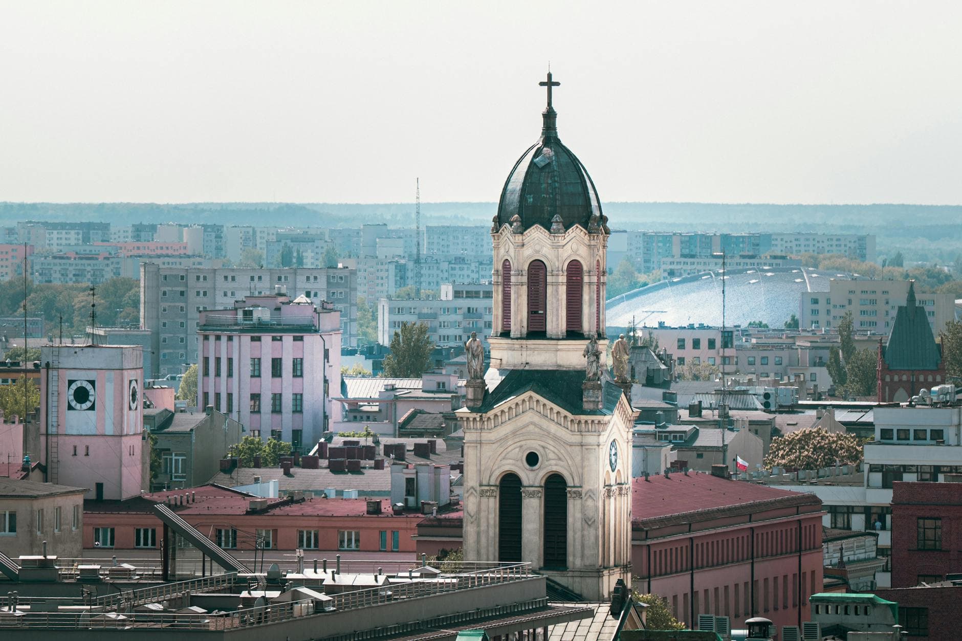 Explore the blend of historic and modern architecture in Łódź, Poland, showcased by this beautiful church tower amidst the city skyline.