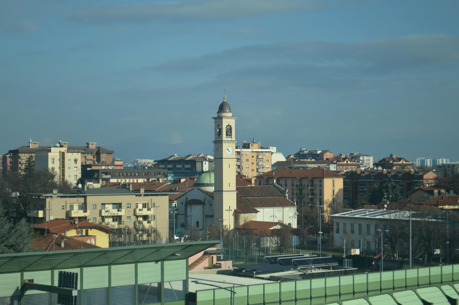 Scenic cityscape with a prominent clock tower against a clear blue sky, showcasing urban architecture.