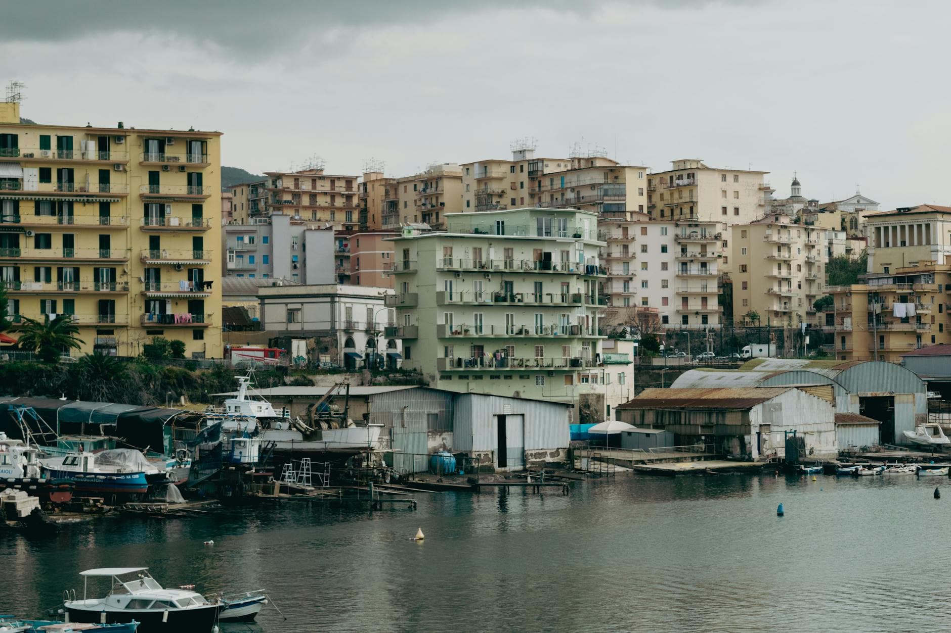 A waterfront view of Naples, Italy, featuring residential buildings and boats.