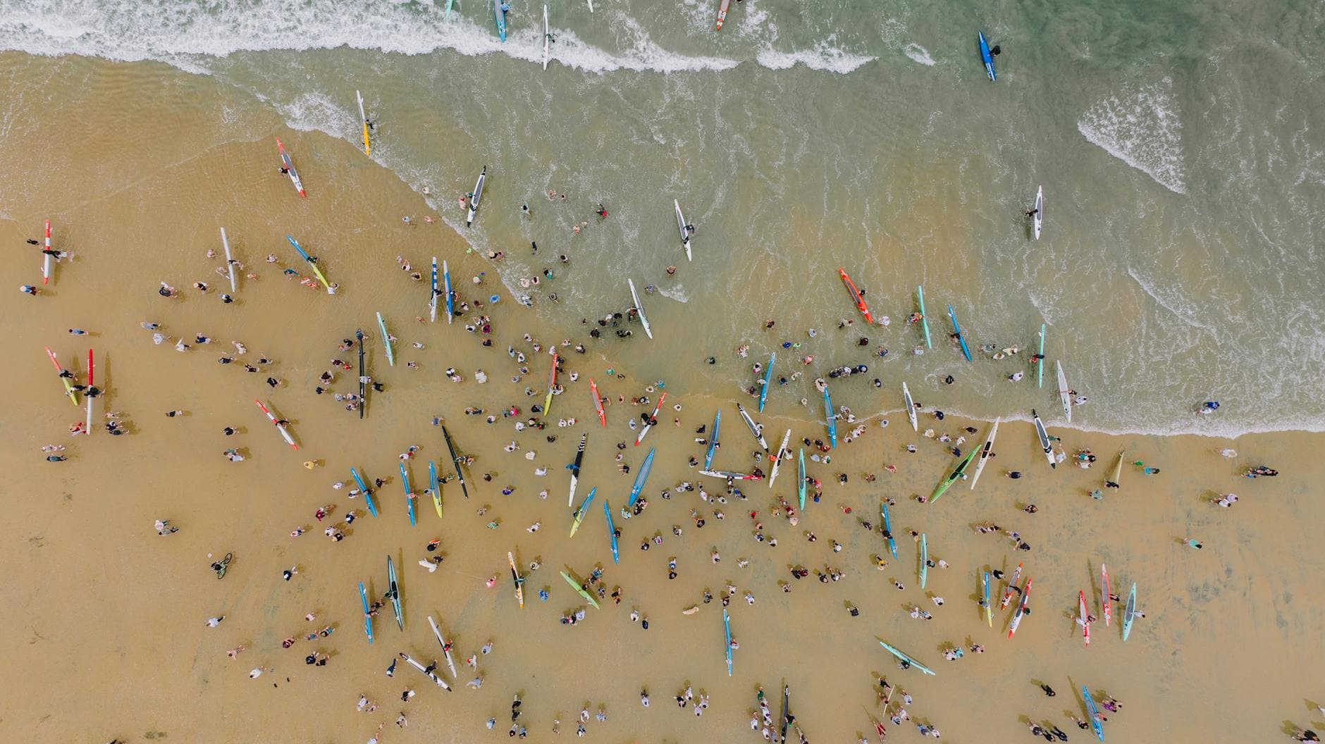 Aerial shot of surfers and beachgoers at Newport Beach, California, enjoying summer leisure.