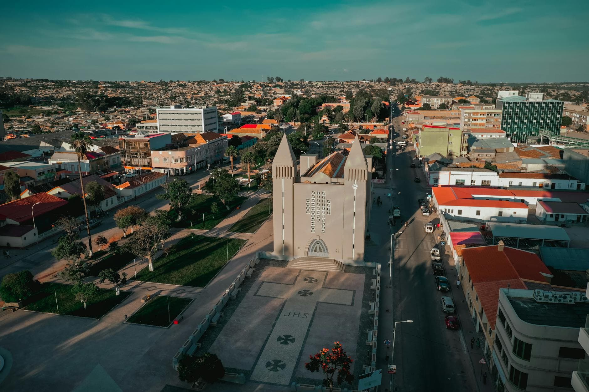 Aerial view of Lubango city with a prominent church in Huíla, Angola under a vibrant blue sky.
