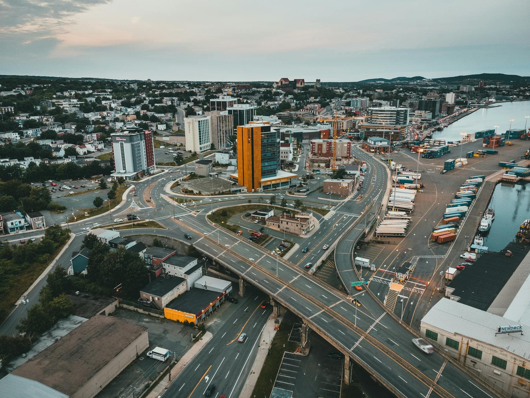 Aerial view highlighting urban cityscape, highways, and waterfront during daytime.