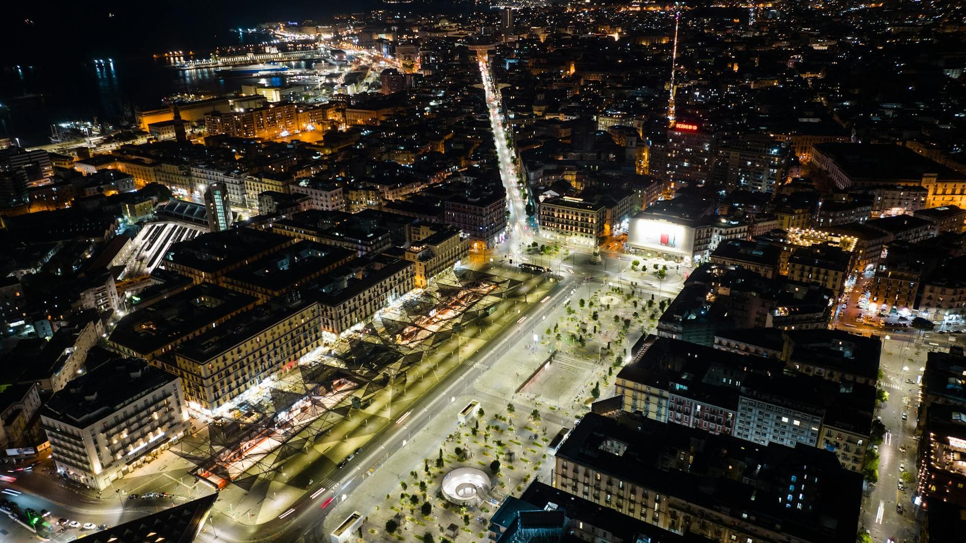 Stunning aerial shot of a vibrant cityscape at night, featuring illuminated streets and diverse architecture.