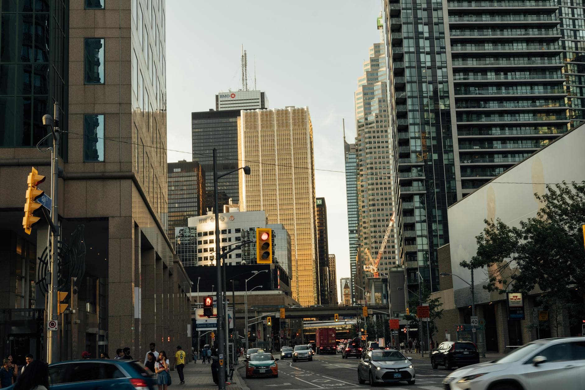 A bustling city street view with towering skyscrapers, vehicles, and pedestrians captured during daytime.