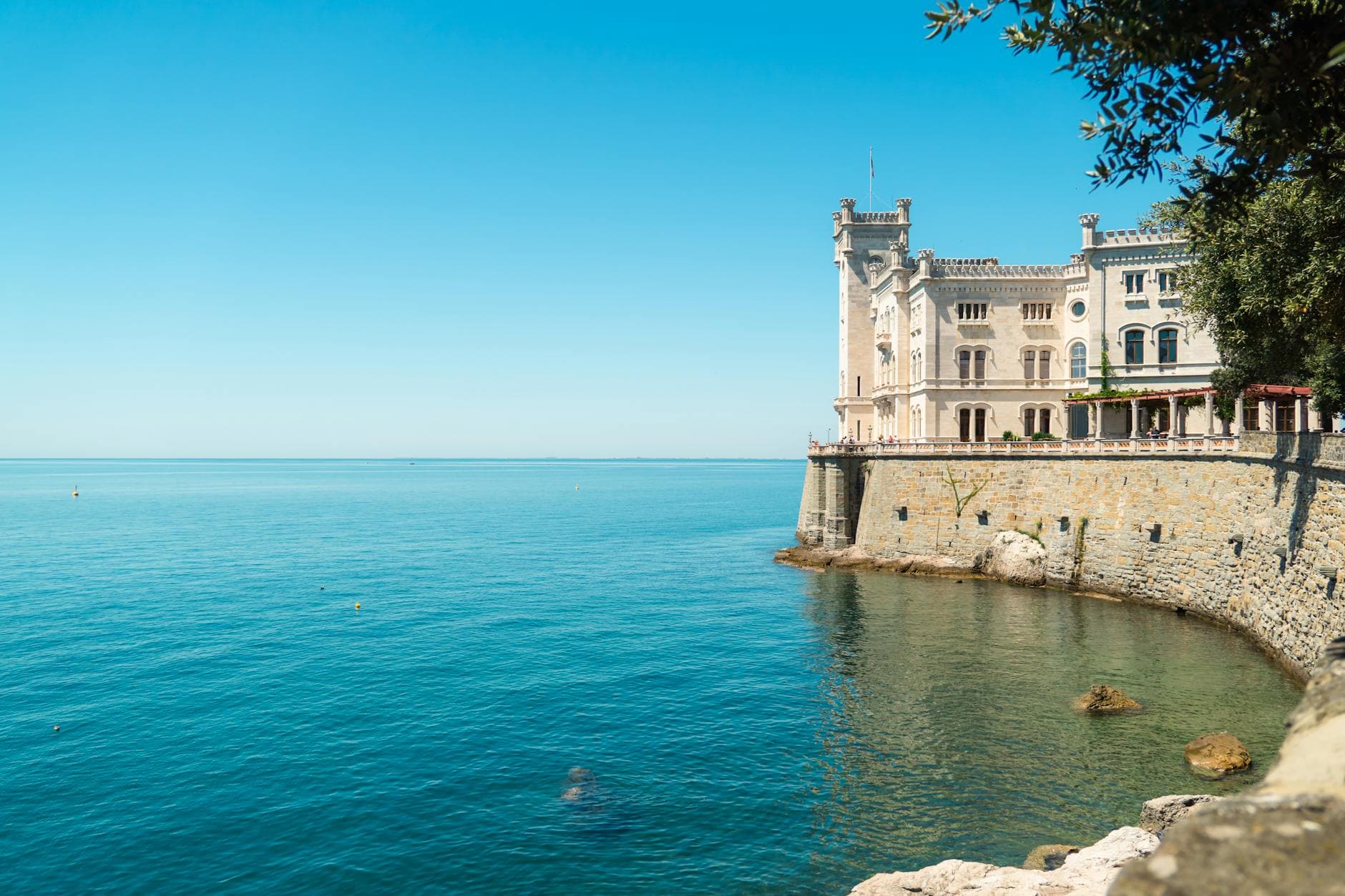 Miramare Castle overlooking the serene Adriatic Sea on a sunny day in Grignano, Italy.