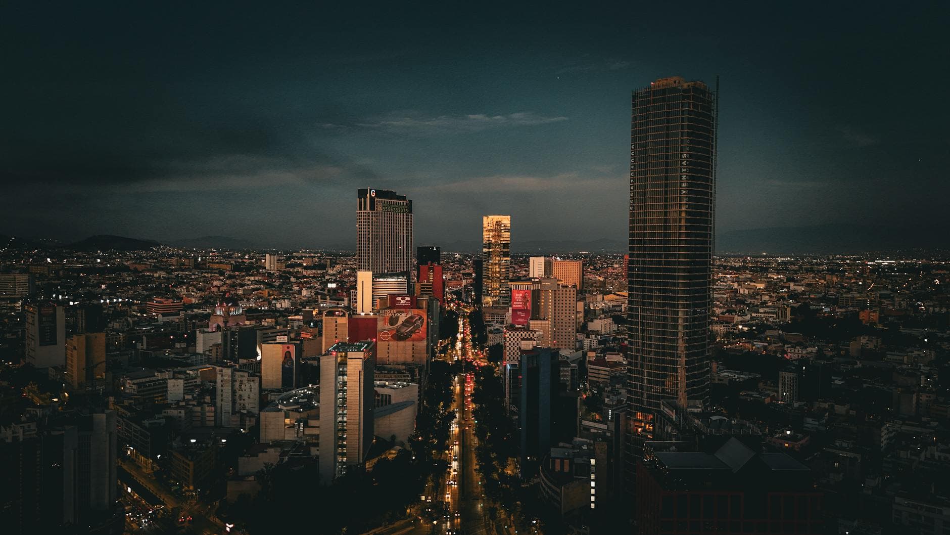 Stunning aerial night view of Mexico City downtown with illuminated skyscrapers and bustling streets.