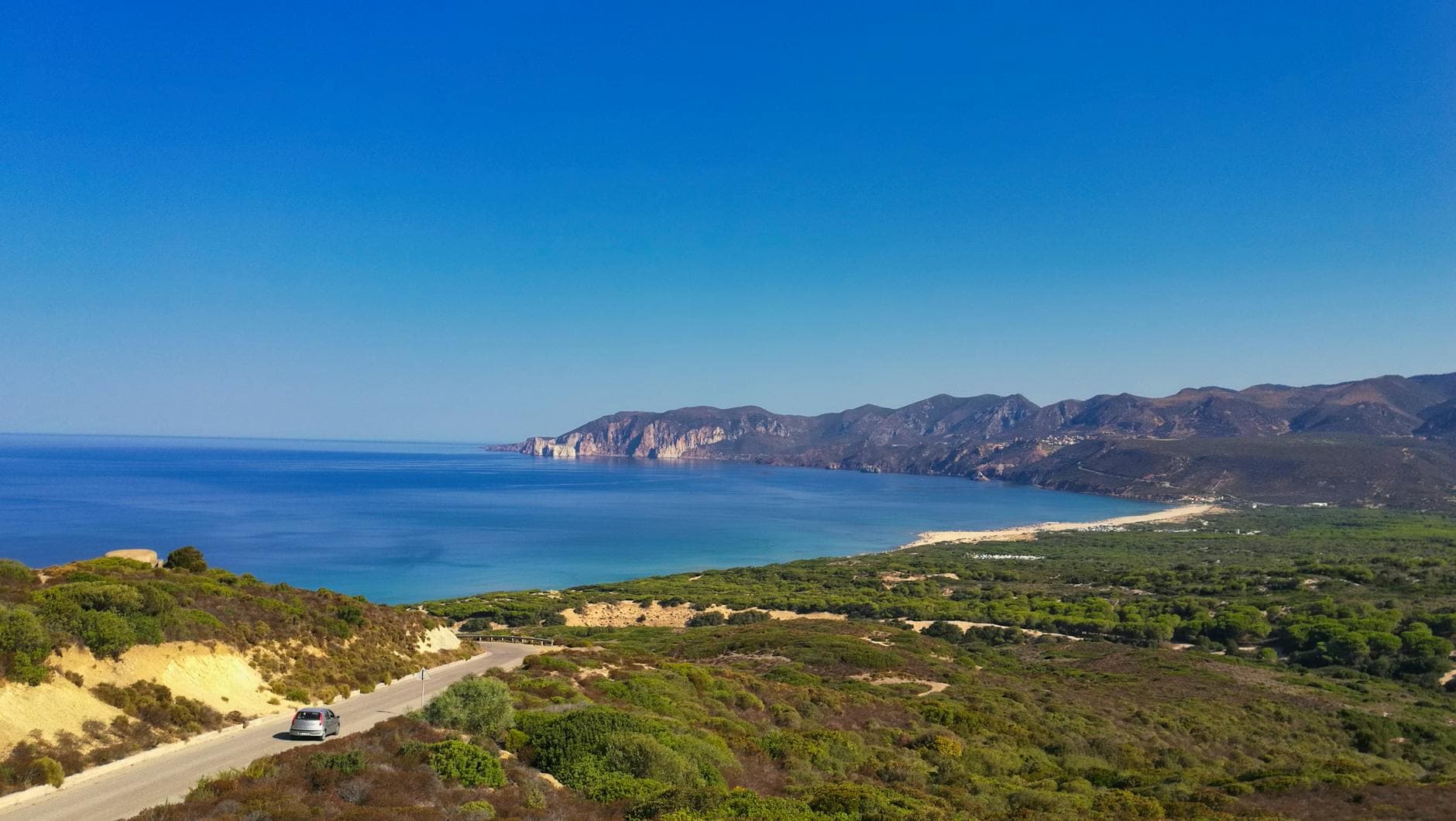 Beautiful panoramic view of the Sardinian coastline with clear blue waters and lush greenery.