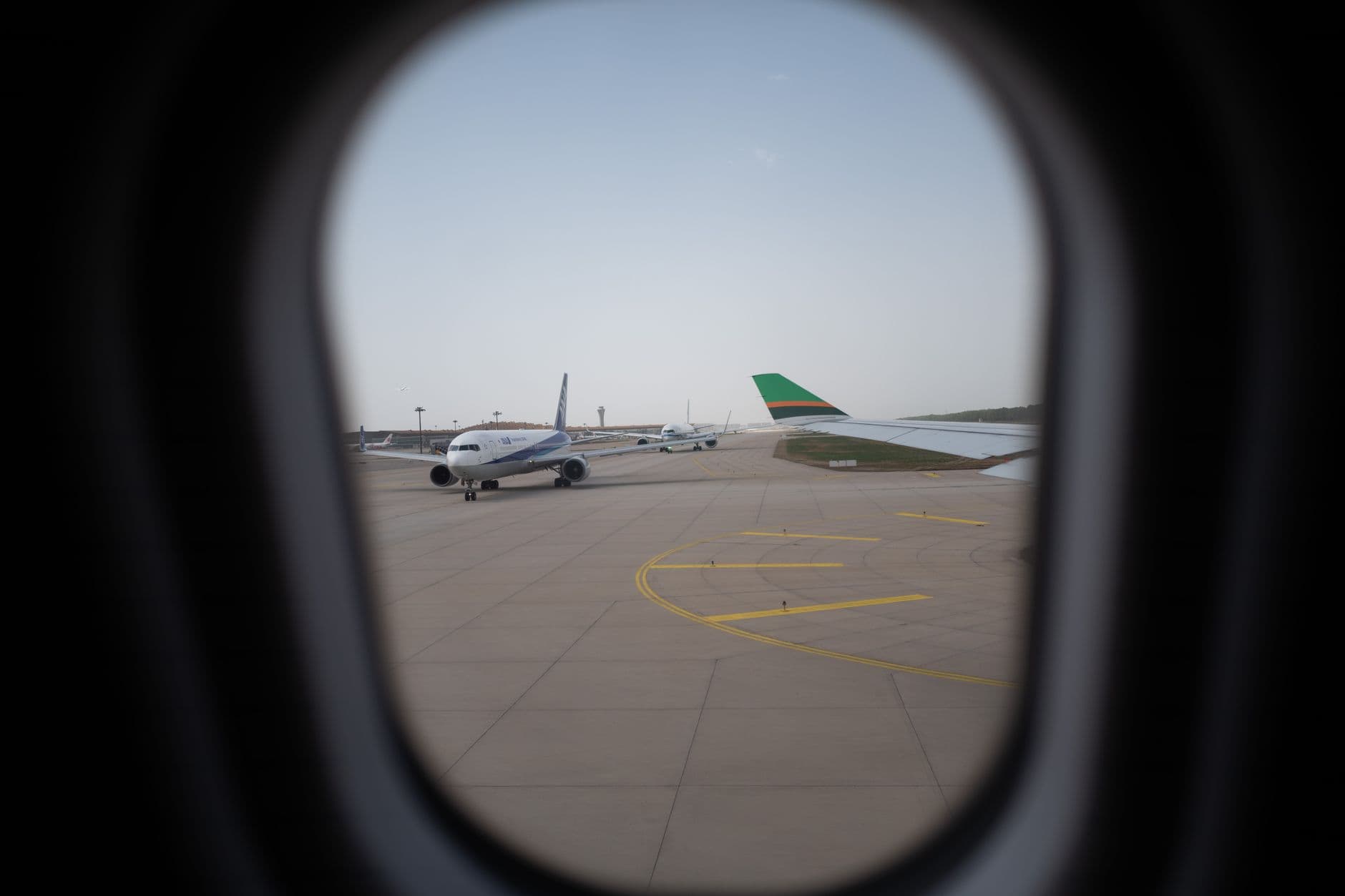 Airplane seen through a window, parked on the airport runway, capturing a travel moment.