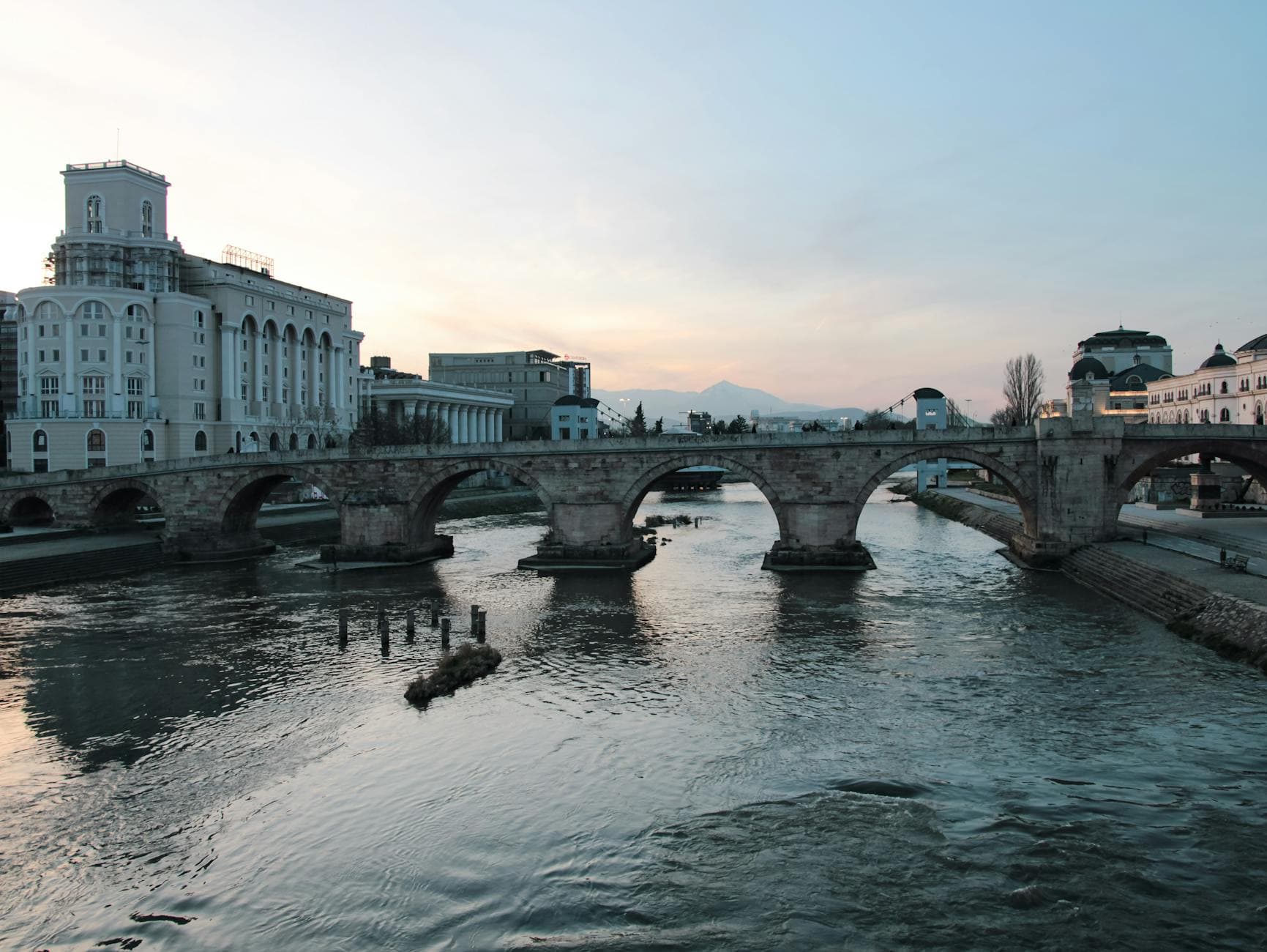 Scenic view of the historical Stone Bridge over the Vardar River in Skopje, North Macedonia during sunset.