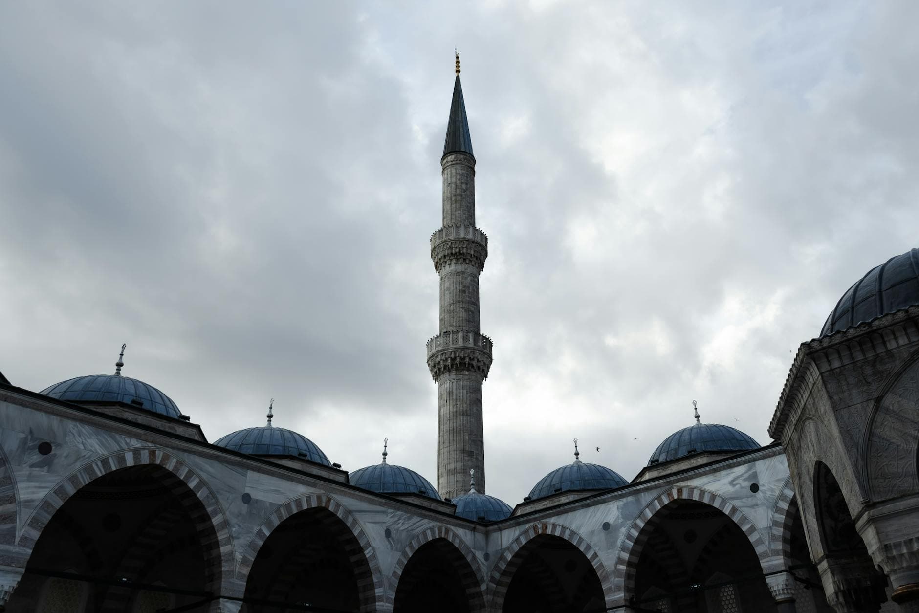 Stunning exterior shot of Sultanahmet Mosque's minaret captured under a cloudy sky in Istanbul.