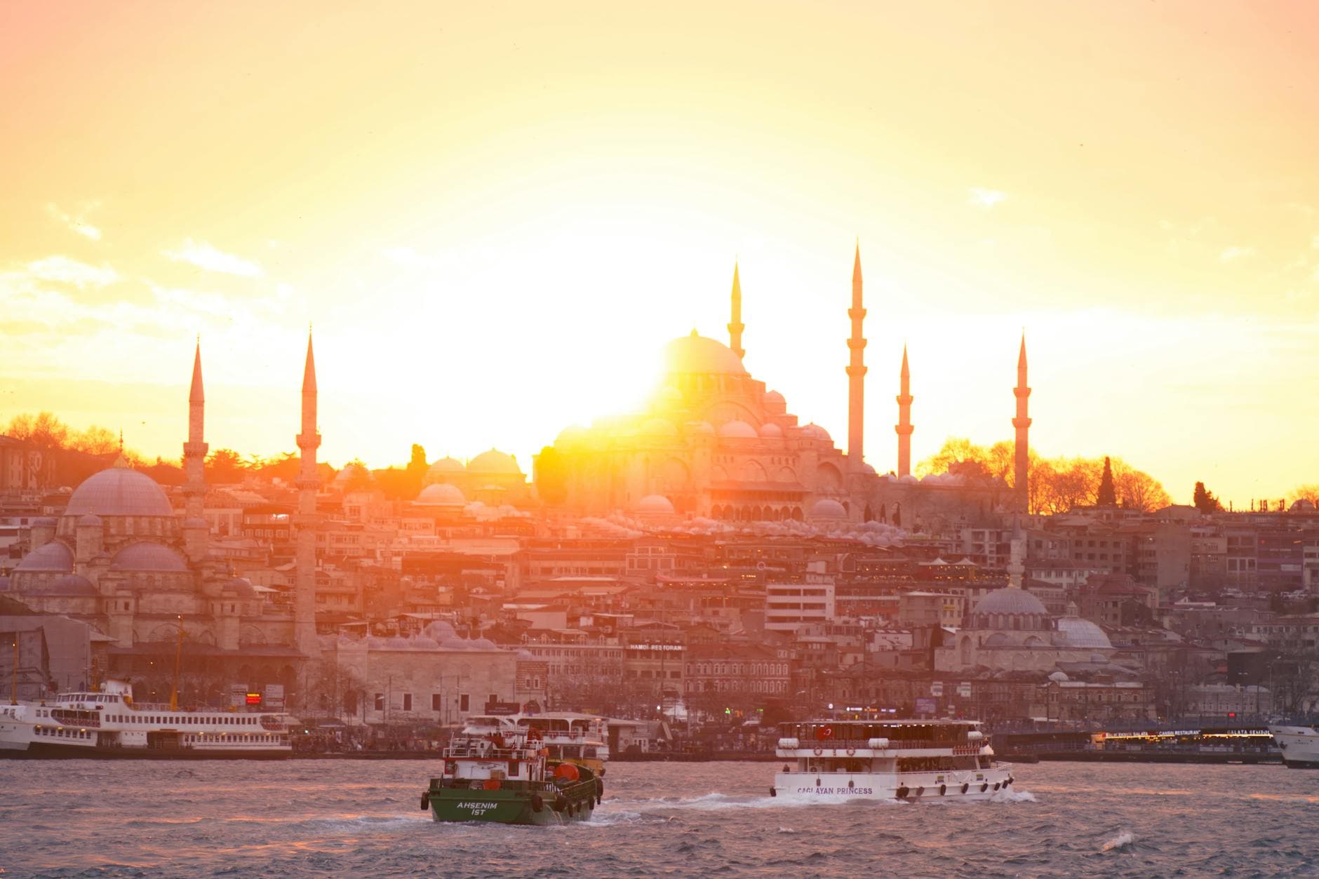 Beautiful sunrise over Istanbul with a mosque's silhouette, viewed from the waterfront.