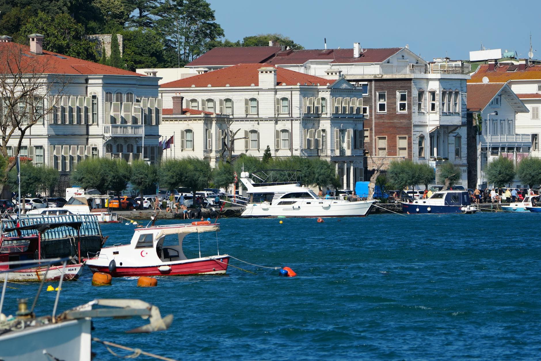Picturesque coastal scene with historic buildings and boats in vibrant blue waters.