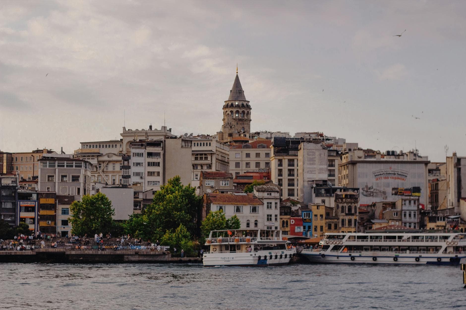 Scenic view of the historic Galata Tower and bustling waterfront in Istanbul, Turkey.
