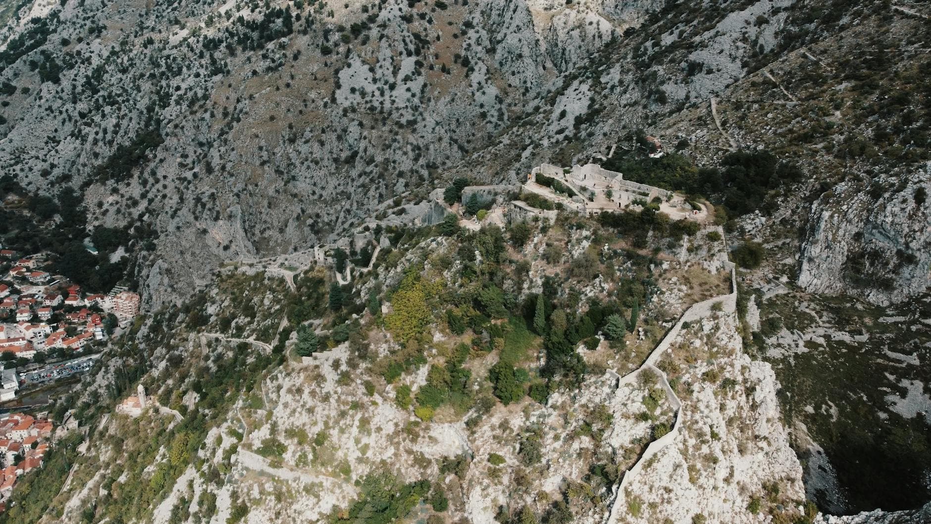 Breathtaking aerial view of the historic Kotor Castle amidst the mountainous landscape of Montenegro.