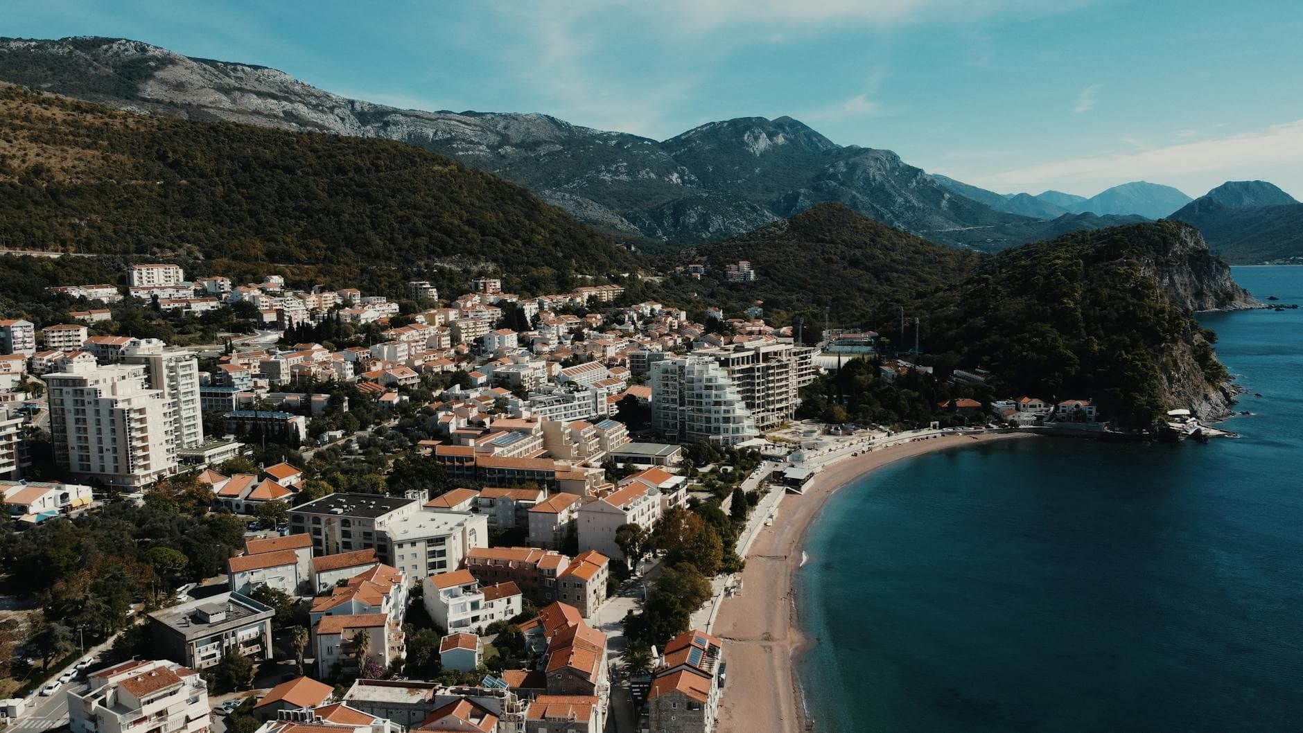 A stunning aerial view of Petrovac, Montenegro, showcasing the beach and surrounding mountains.