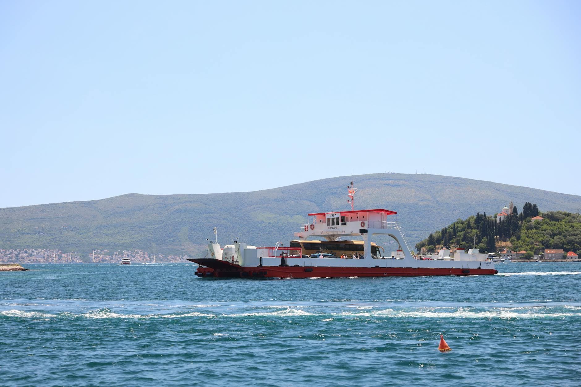 A ferry crossing scenic bay waters with mountainous background, perfect for travel exploration.