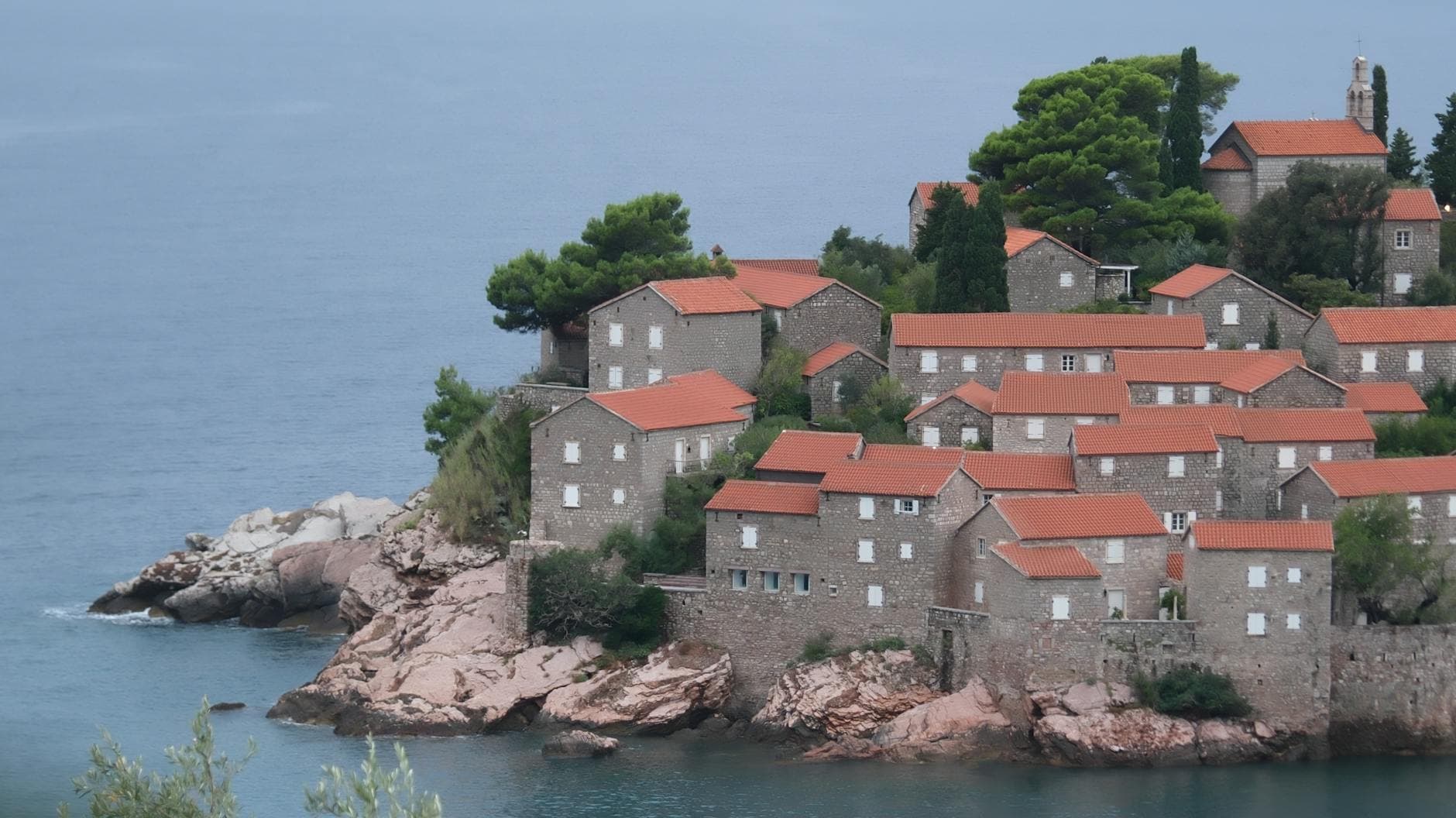 Stunning coastal landscape of historic Sveti Stefan, Montenegro with stone houses and red roofs.
