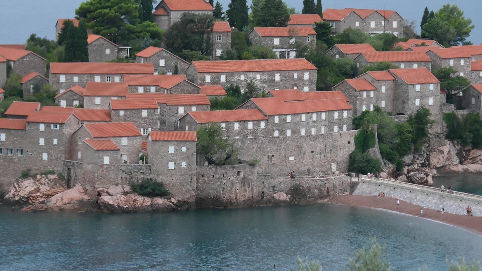 Explore the picturesque Sveti Stefan with its historic red-roofed buildings by the sea.