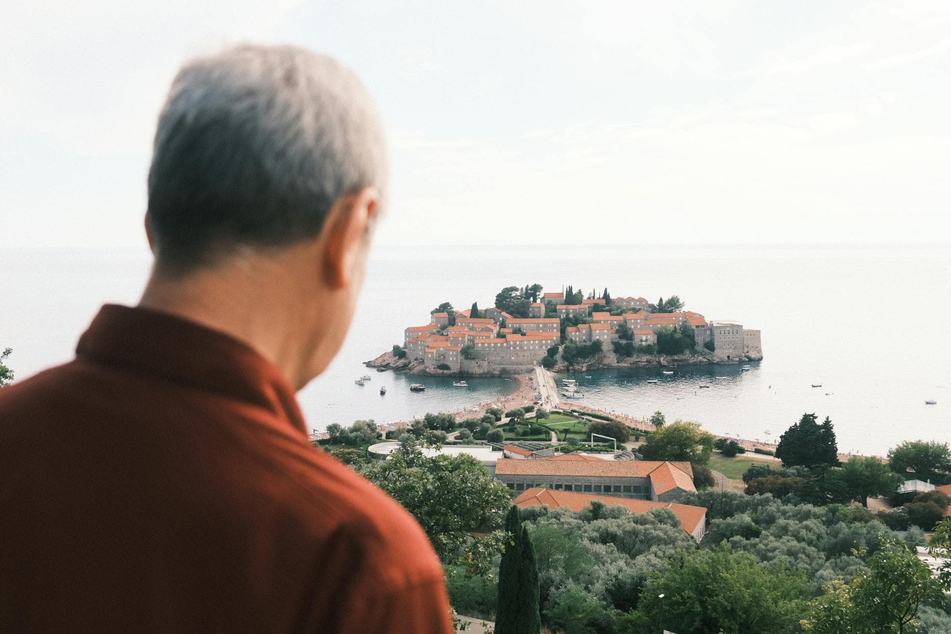 A man gazes at the picturesque Sveti Stefan Island in Montenegro, a historic coastal landmark.