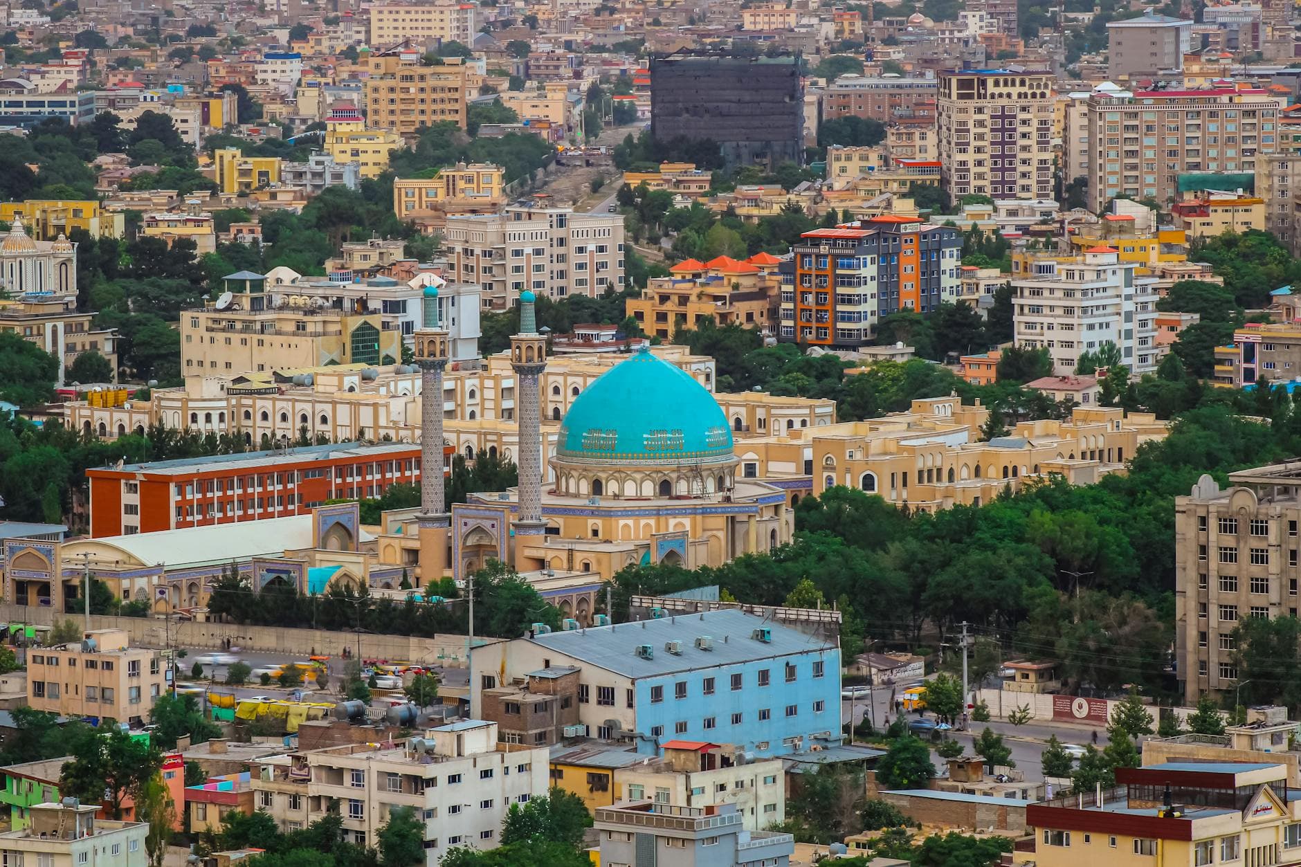 Colorful cityscape of Kabul with a prominent mosque and urban landscape.