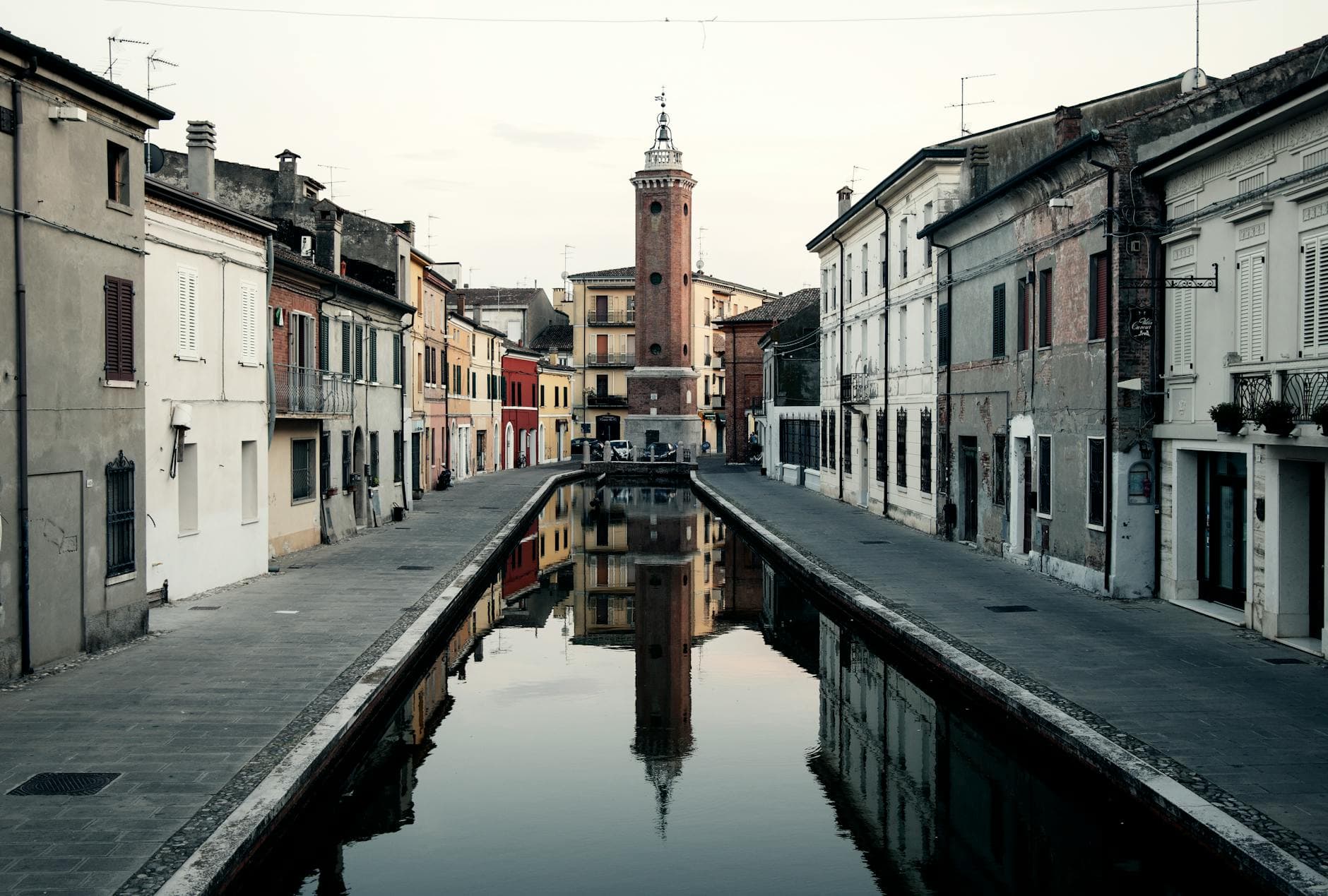 Explore the picturesque Trepponti Bridge reflection on the water in Comacchio, Italy's historic city at sunset.