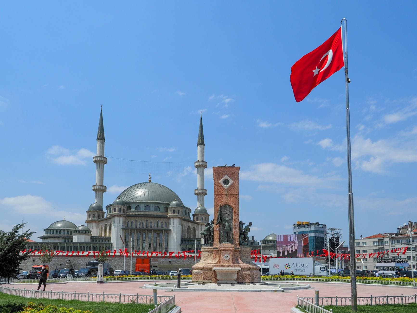 Stunning view of Taksim Square featuring the mosque and Republic Monument under a clear blue sky.