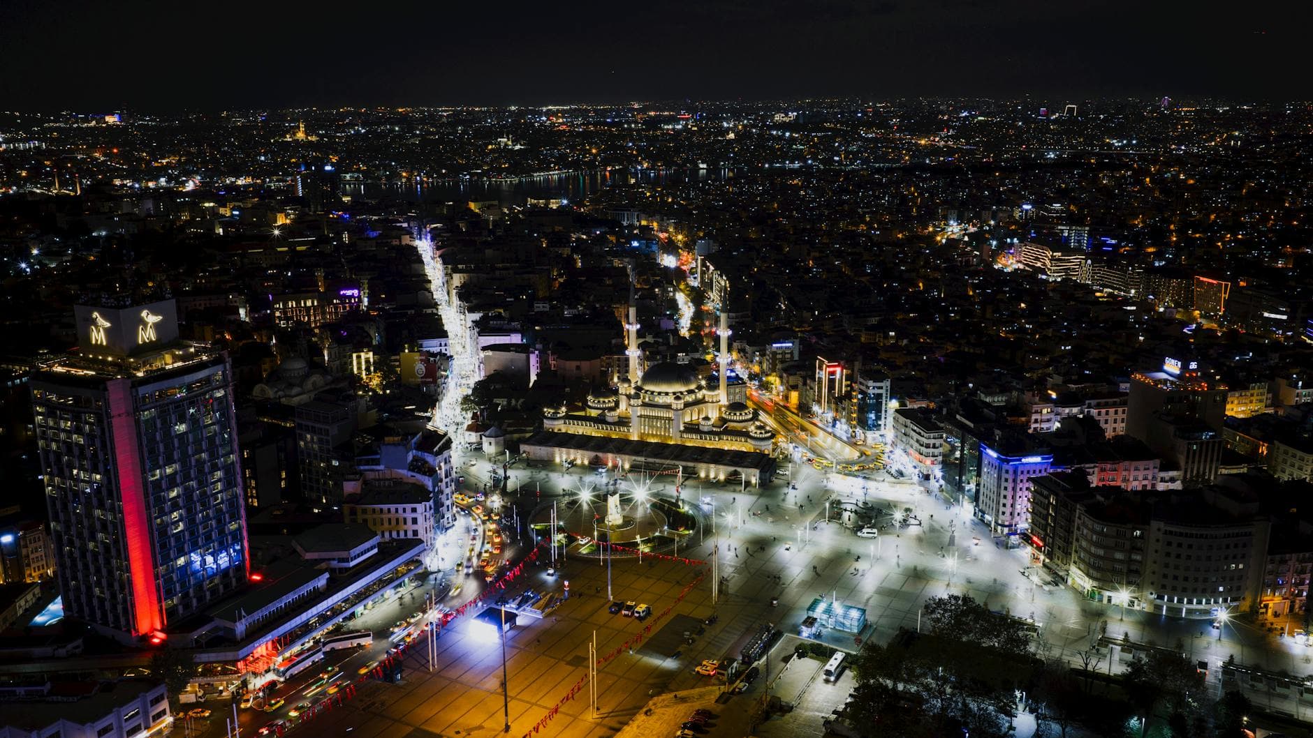 Aerial view of Taksim Square in Istanbul at night, showcasing city lights and bustling streets.