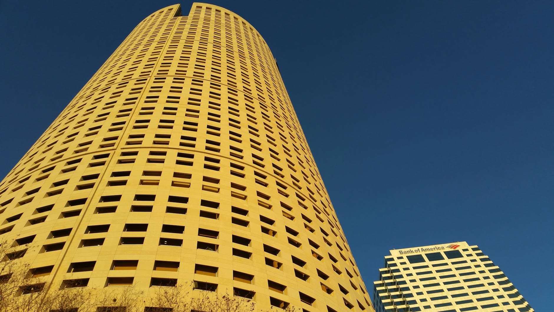 Low-angle view of Rivergate Tower and nearby skyscraper in downtown Tampa under a clear blue sky.