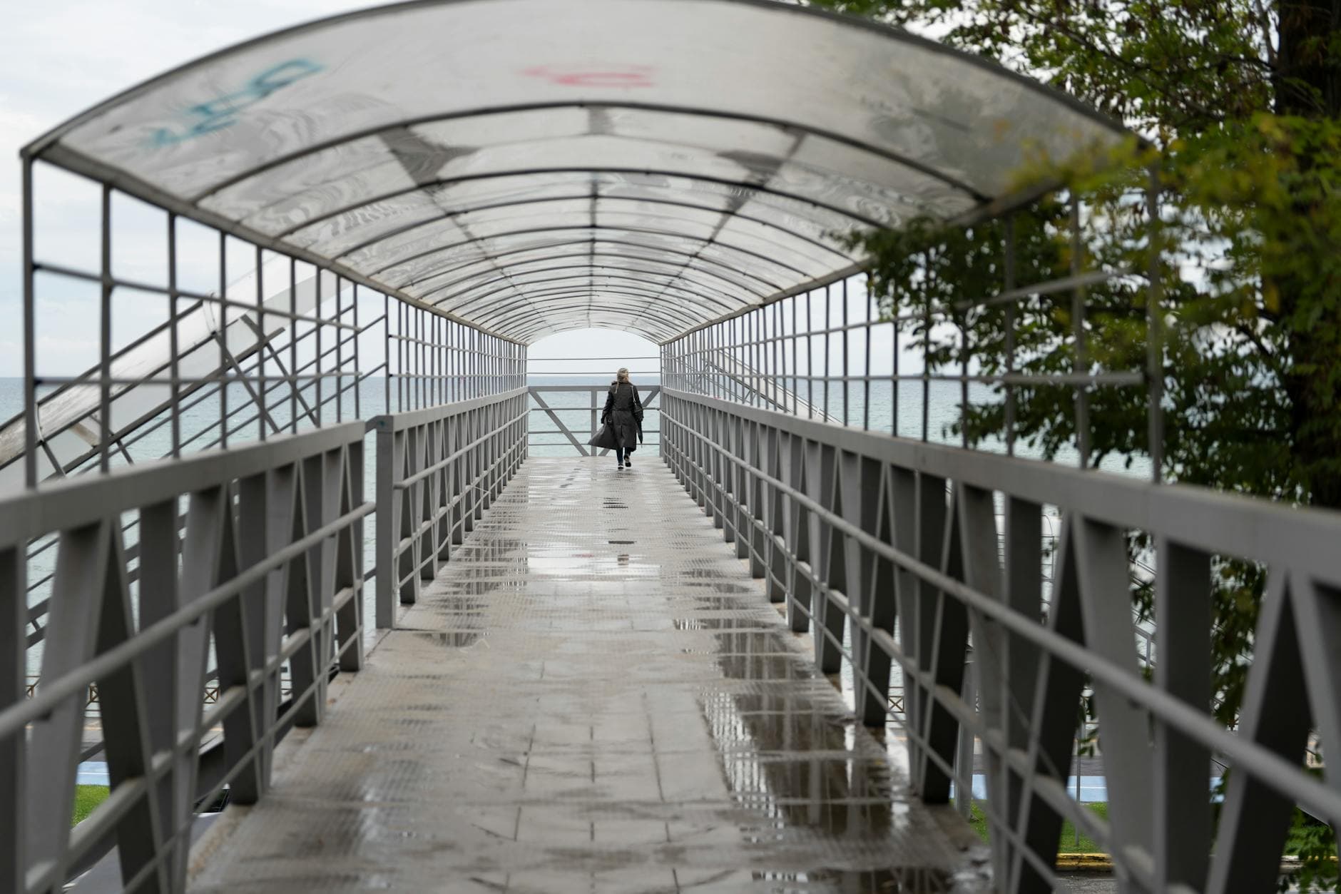 A woman walks on a covered pedestrian bridge overlooking the sea in Tekirdağ, Türkiye.