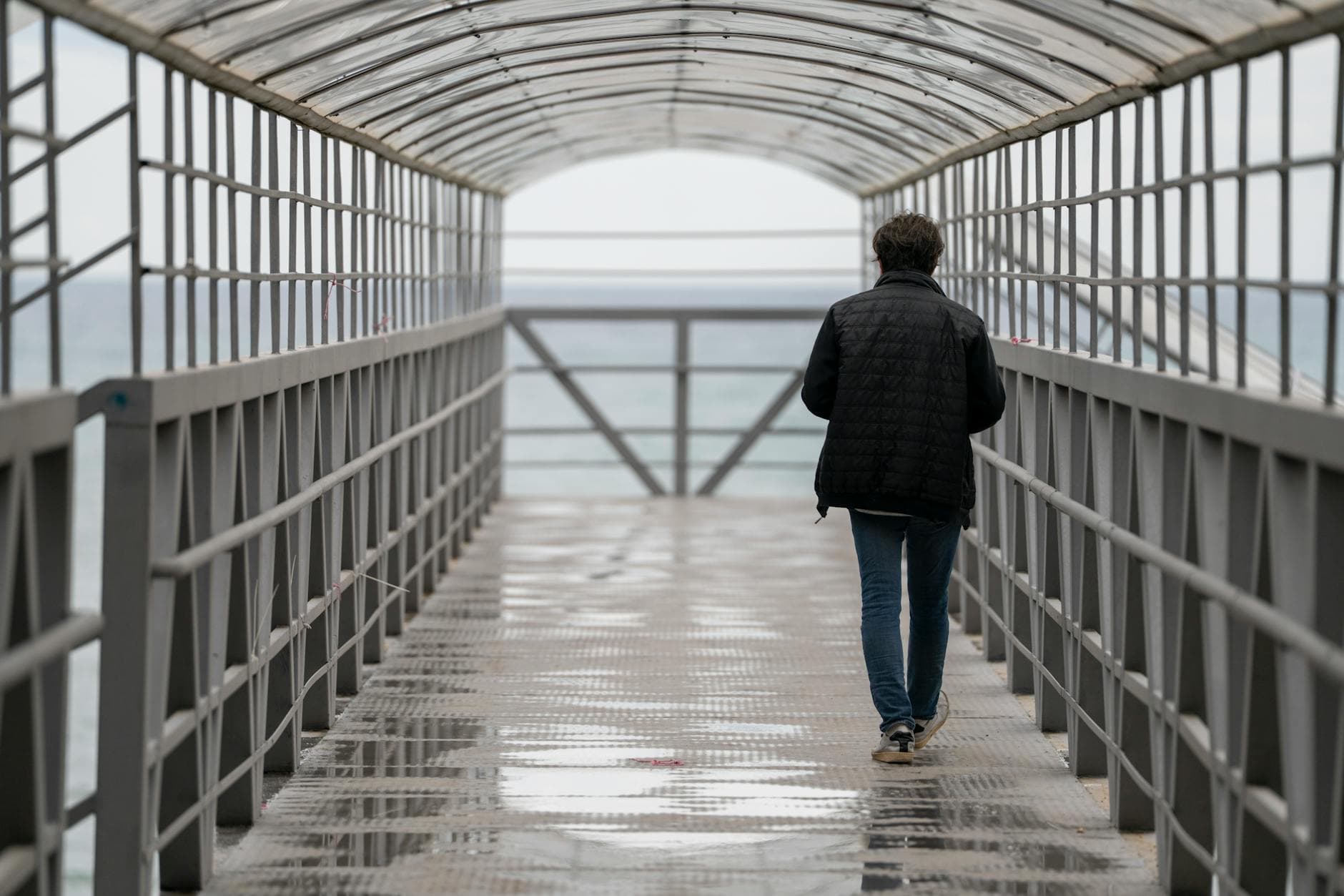 A person walks on a covered metal bridge with a sea view in Tekirdağ, Türkiye.