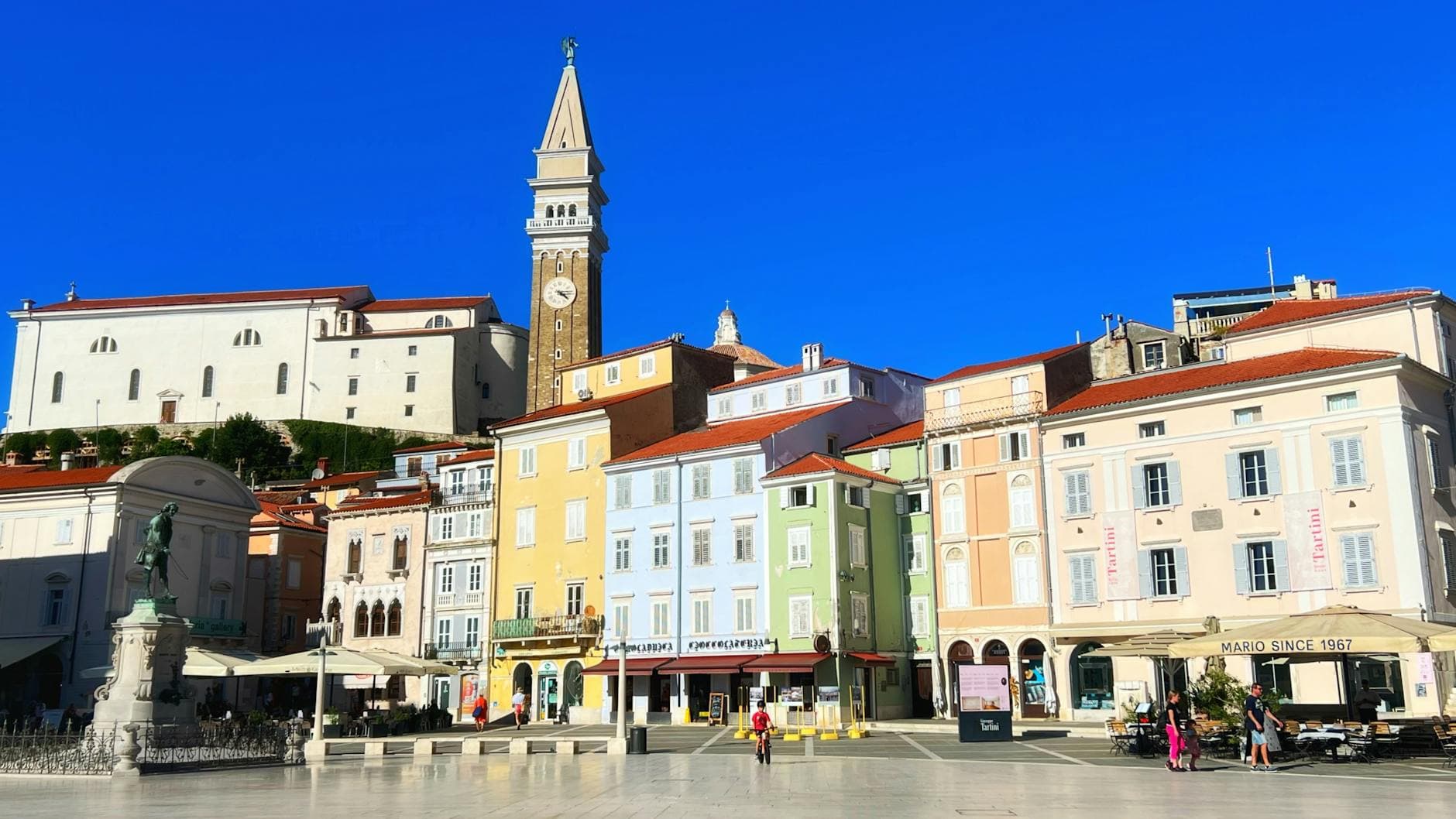 A vibrant view of Tartini Square in Piran, Slovenia, showcasing colorful architecture and a prominent bell tower.