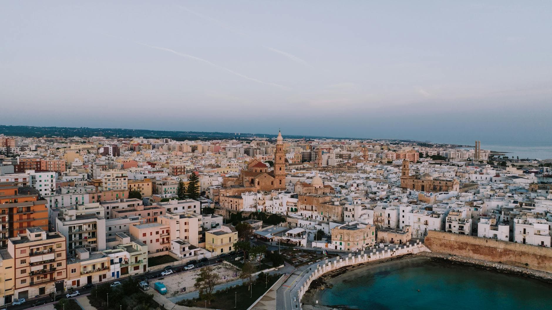 A stunning aerial cityscape of Monopoli, Puglia, Italy, showcasing coastal architecture at dusk.