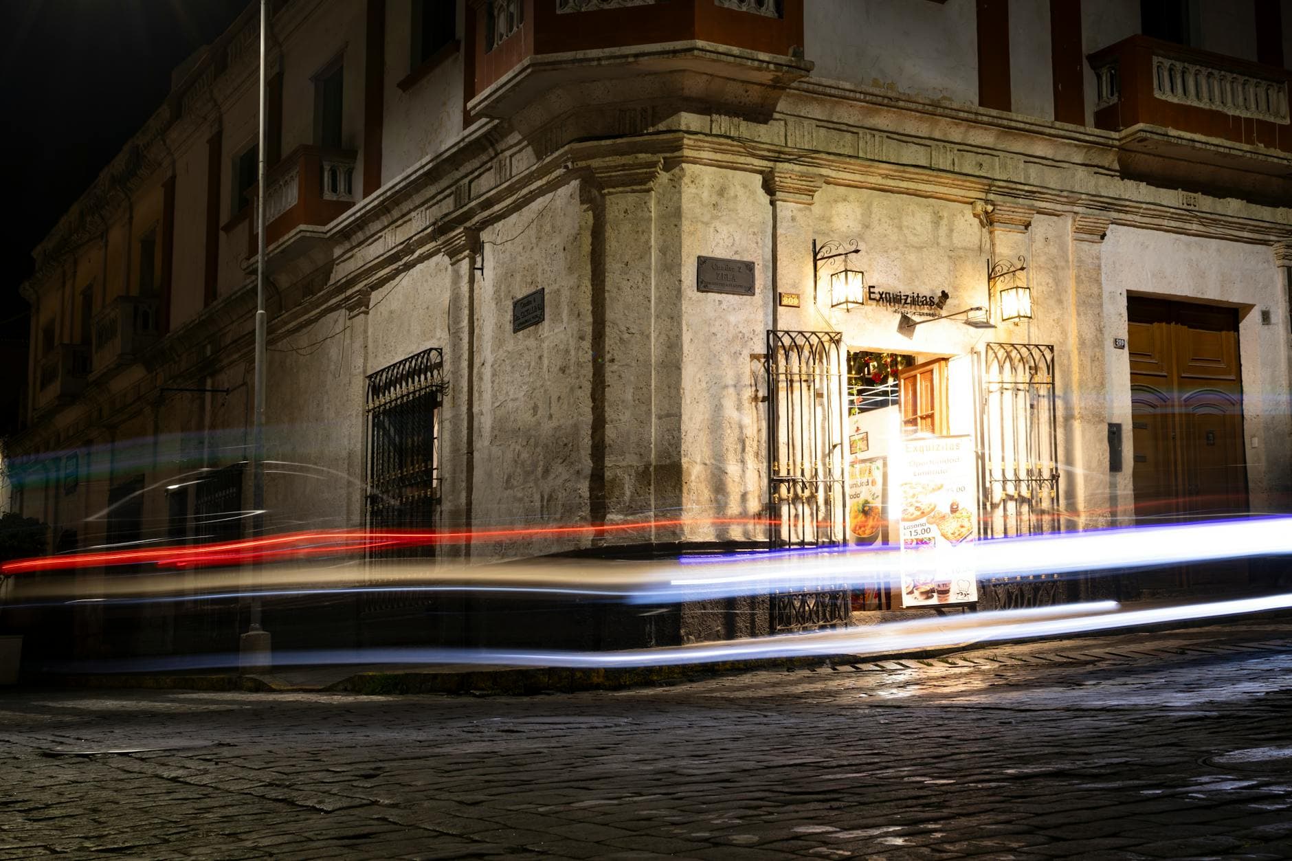 Long exposure captures moving lights against Arequipa's historic colonial architecture at night.