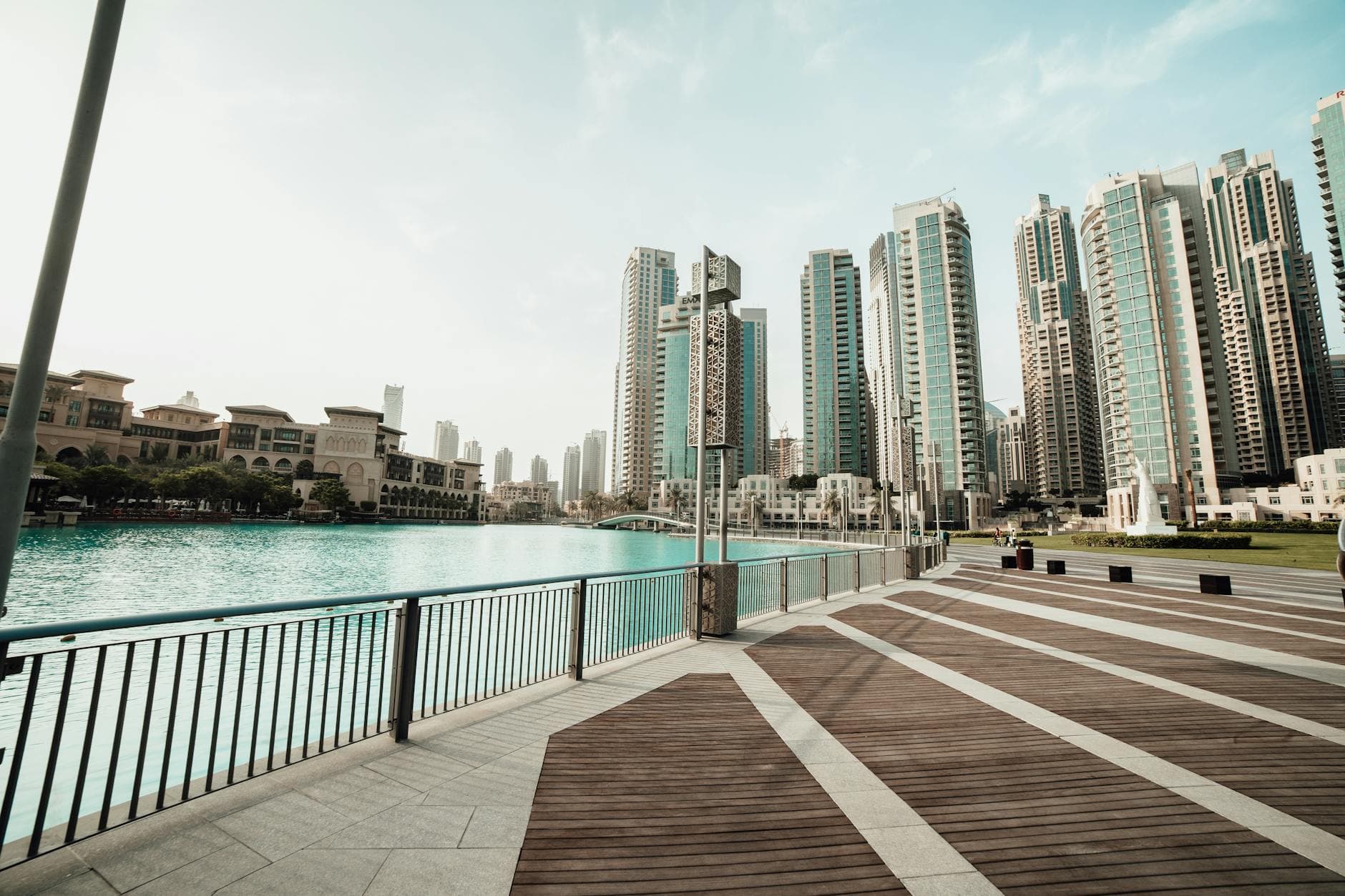 Majestic skyscrapers lining a tranquil waterfront in downtown Dubai, UAE, on a sunny day.