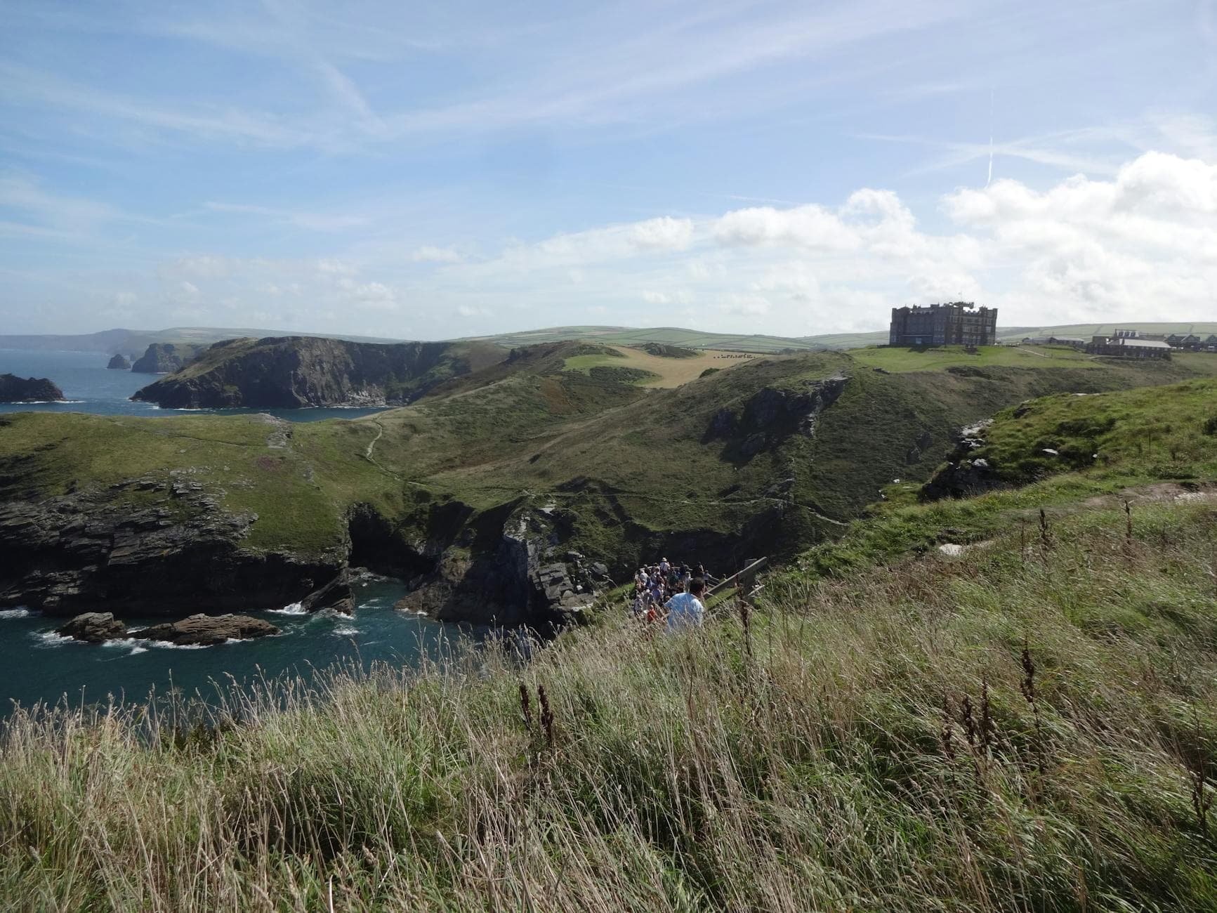 Beautiful landscape of Tintagel, Cornwall with cliffs and castle ruins under a bright sky.
