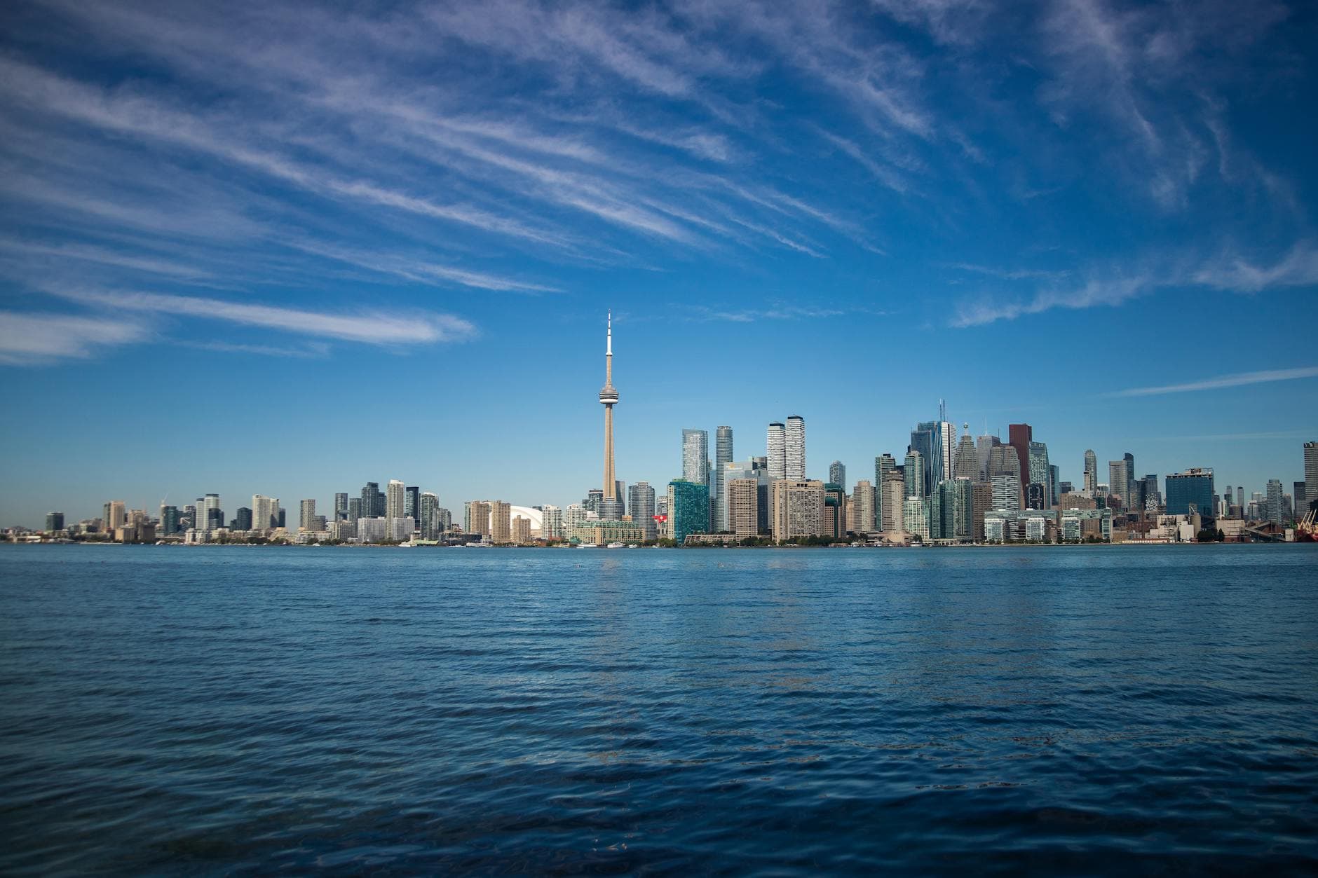 Scenic view of Toronto city skyline featuring the CN Tower and waterfront under a clear blue sky.