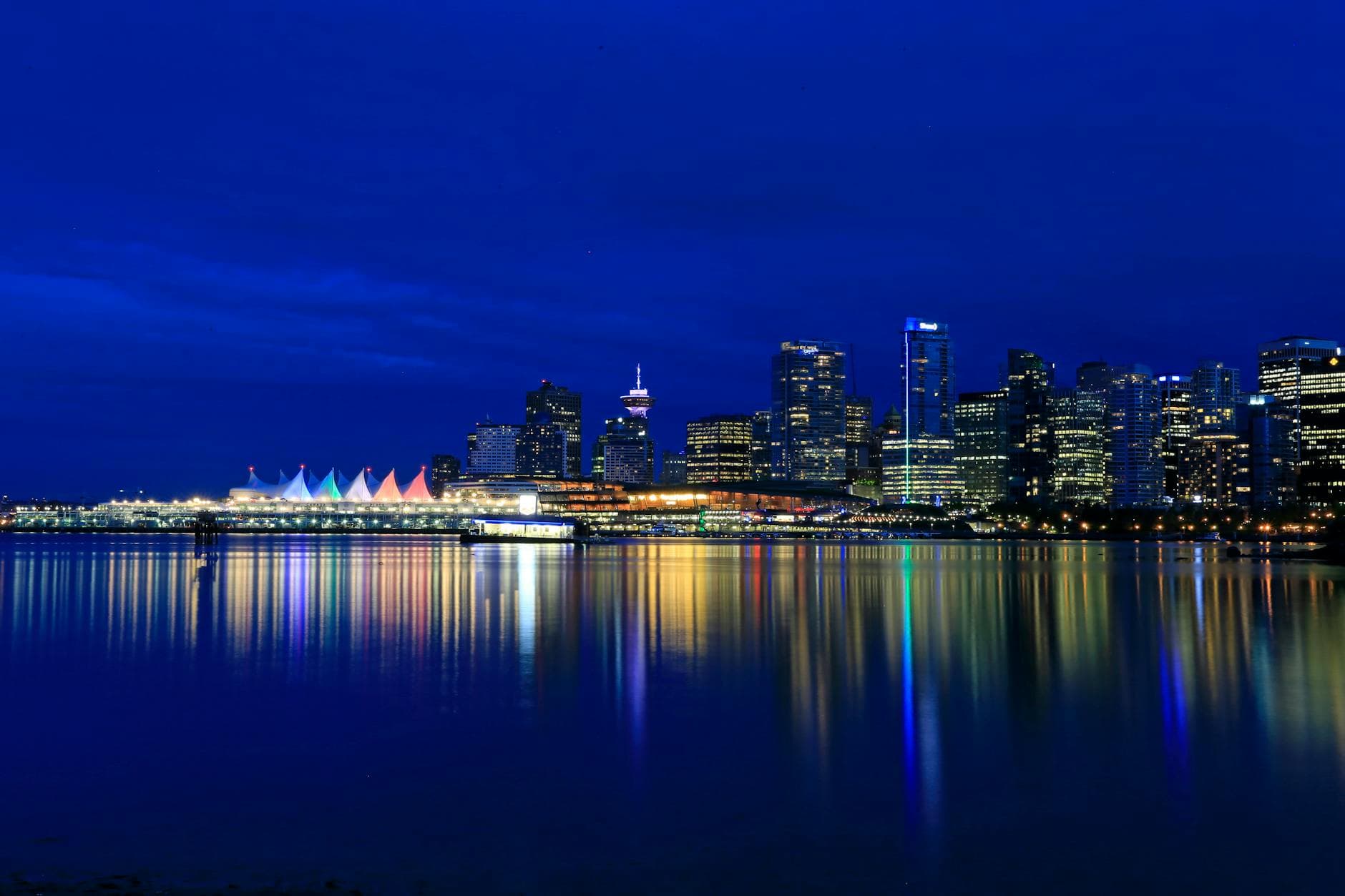 Vibrant night view of Vancouver's illuminated skyline reflecting in the calm waterfront.