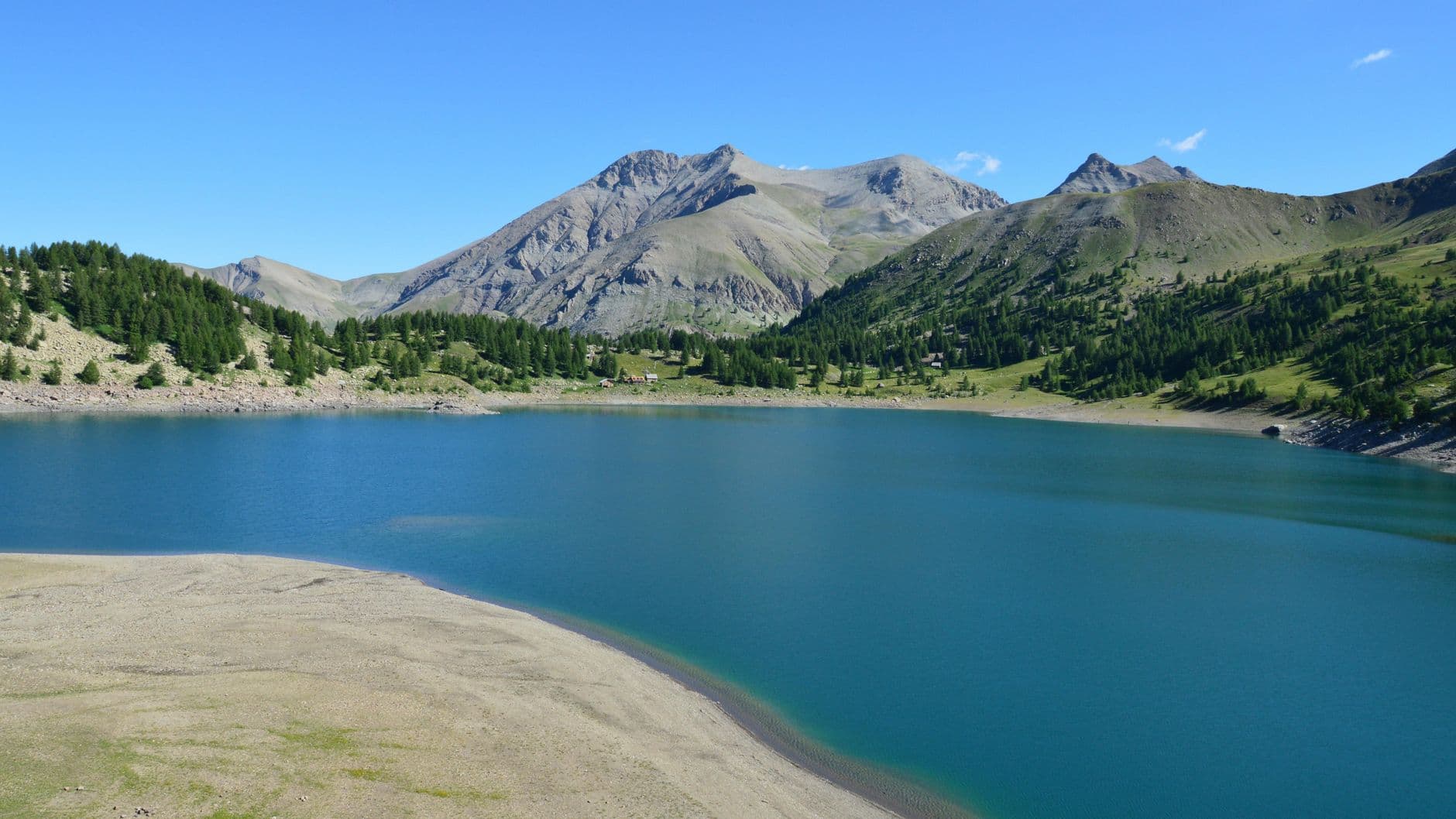 A serene alpine lake surrounded by towering mountains under clear blue skies.
