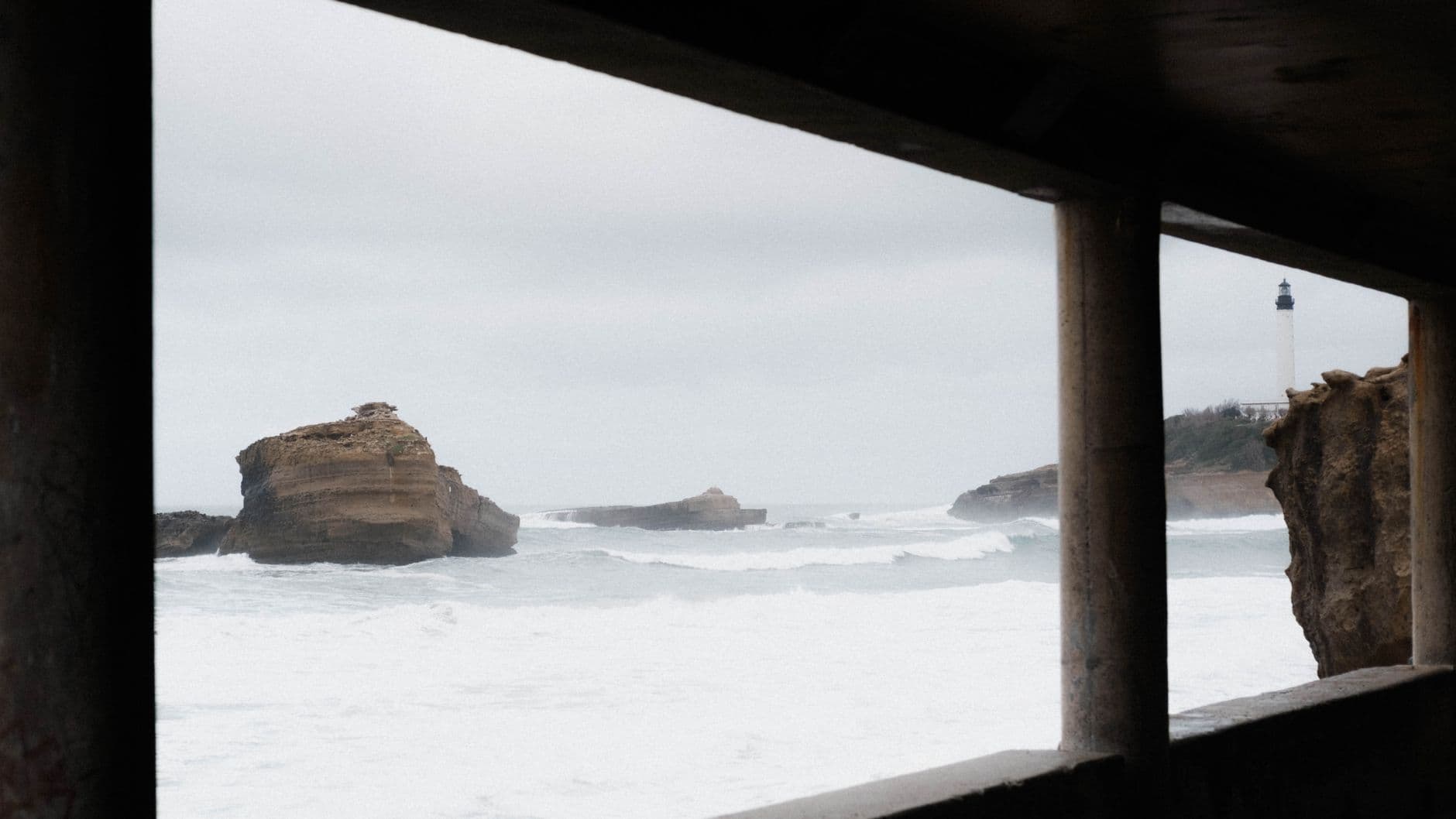 Scenic view of Biarritz Lighthouse through a frame with rocky ocean waves.
