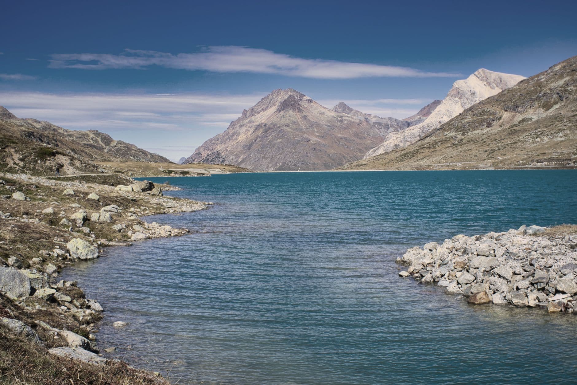 A serene mountain lake with rocky shores under a clear blue sky.
