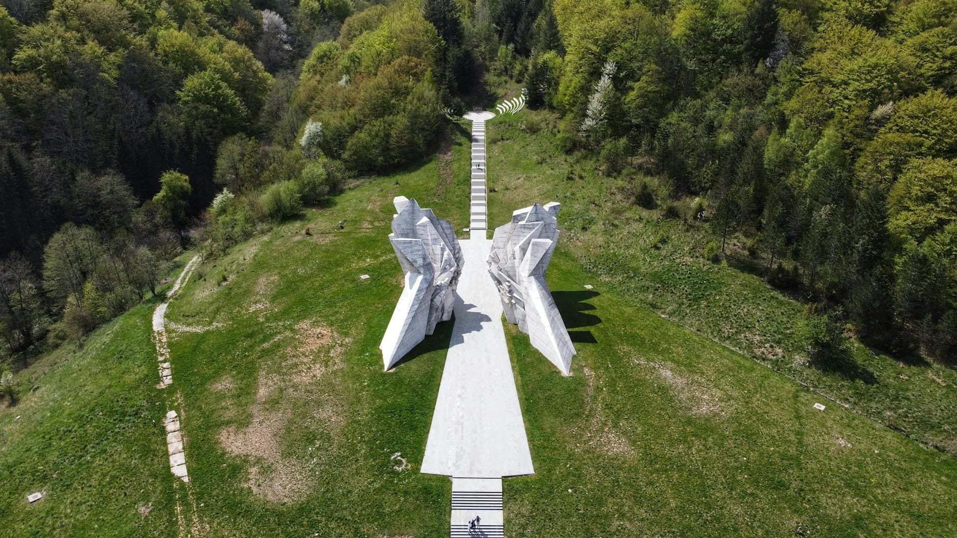 A striking aerial view of the Tjentište monument in Bosnia, surrounded by lush greenery.