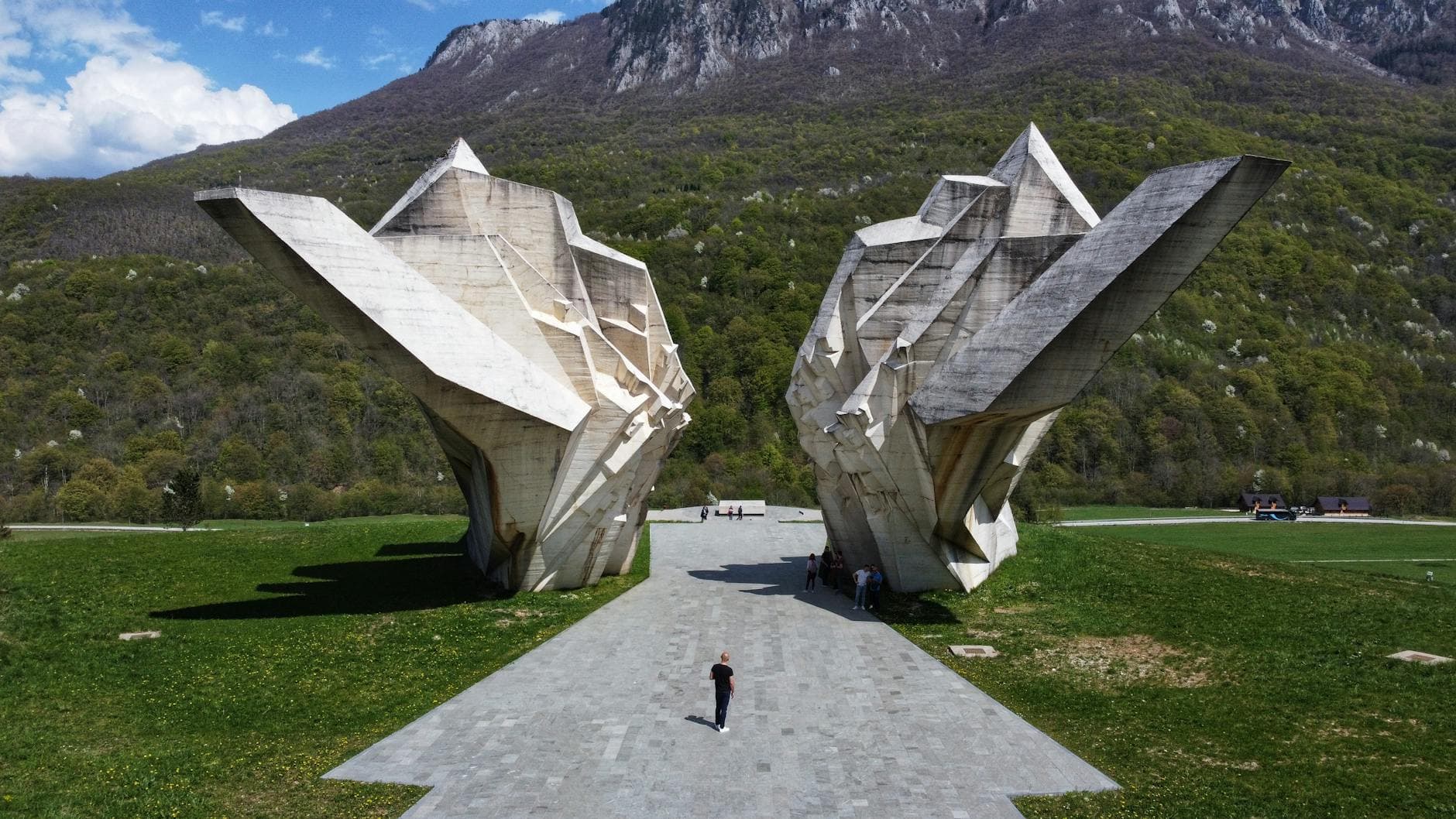 A striking view of the Sutjeska Monument in Tjentište Valley, Bosnia, surrounded by mountains.