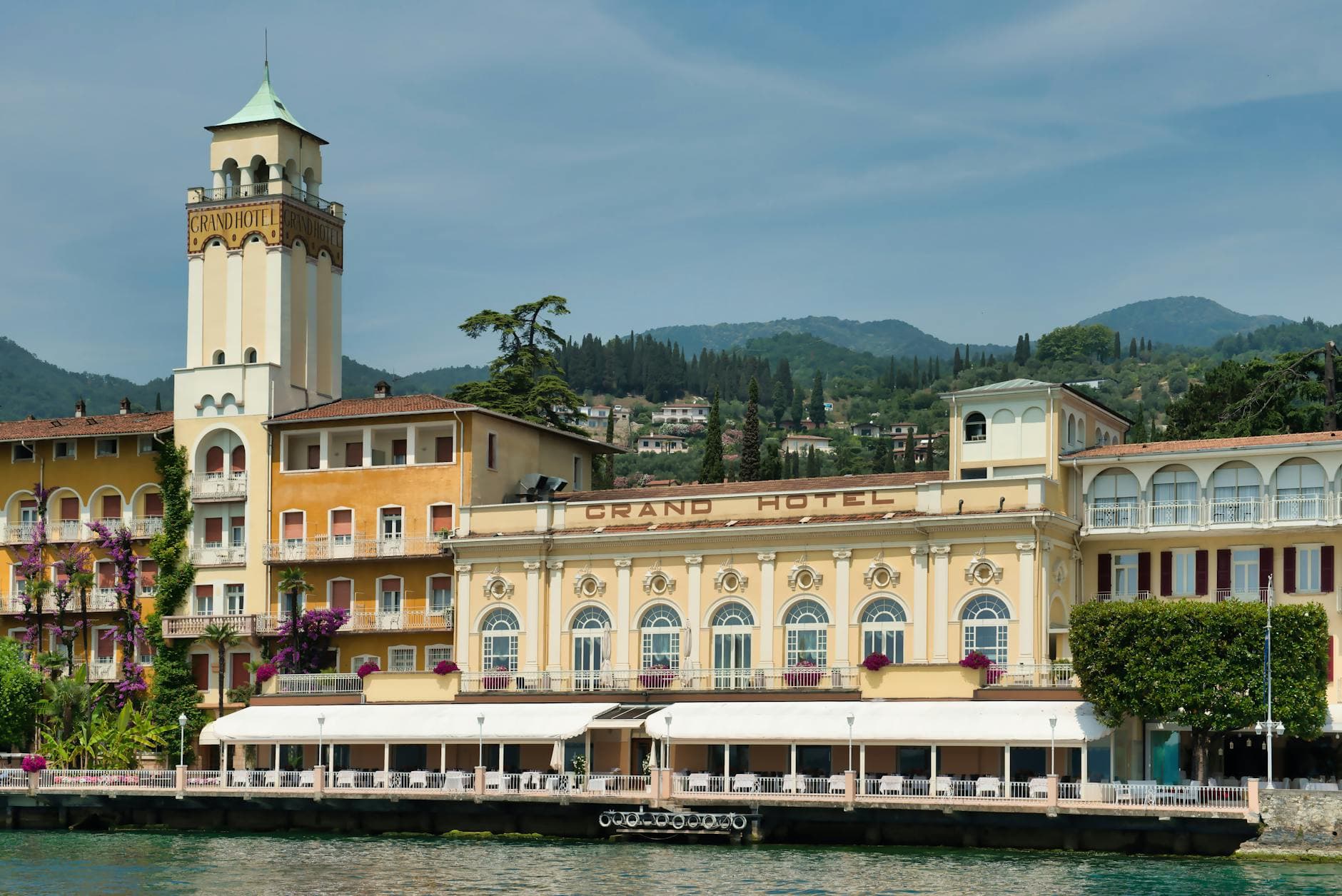 Historic Grand Hotel overlooking beautiful Lake Garda in Italy with scenic mountain backdrop.